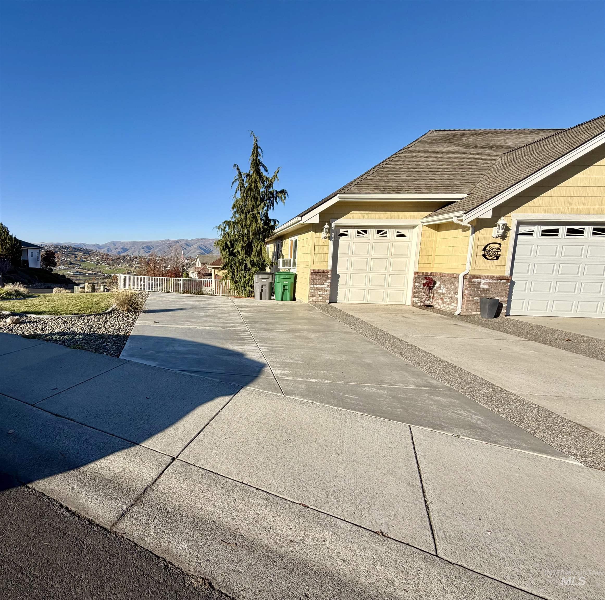 View of property exterior featuring concrete driveway, a shingled roof, a garage, and a mountain view