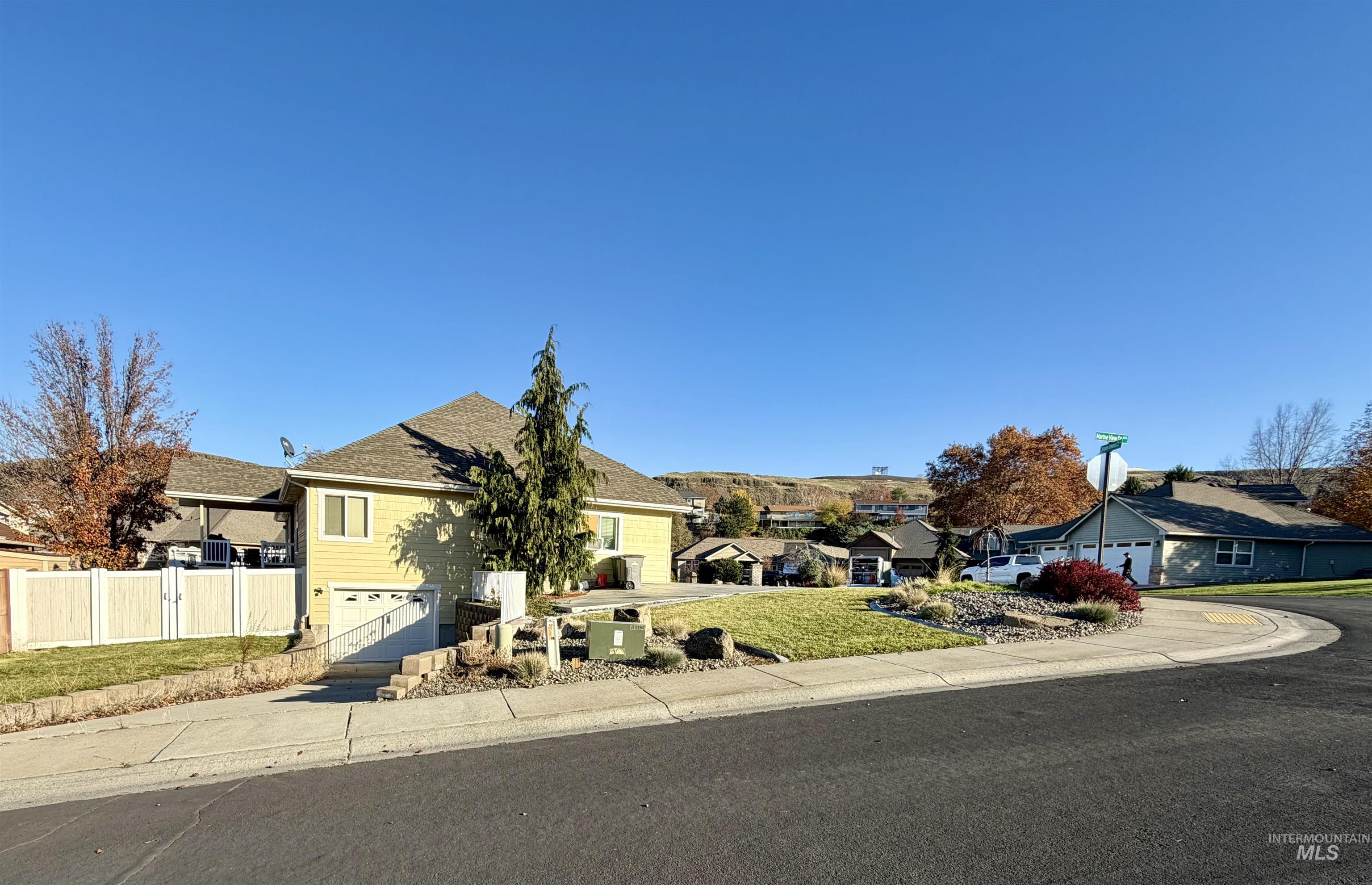 View of front of property with driveway, a residential view, roof with shingles, and a garage