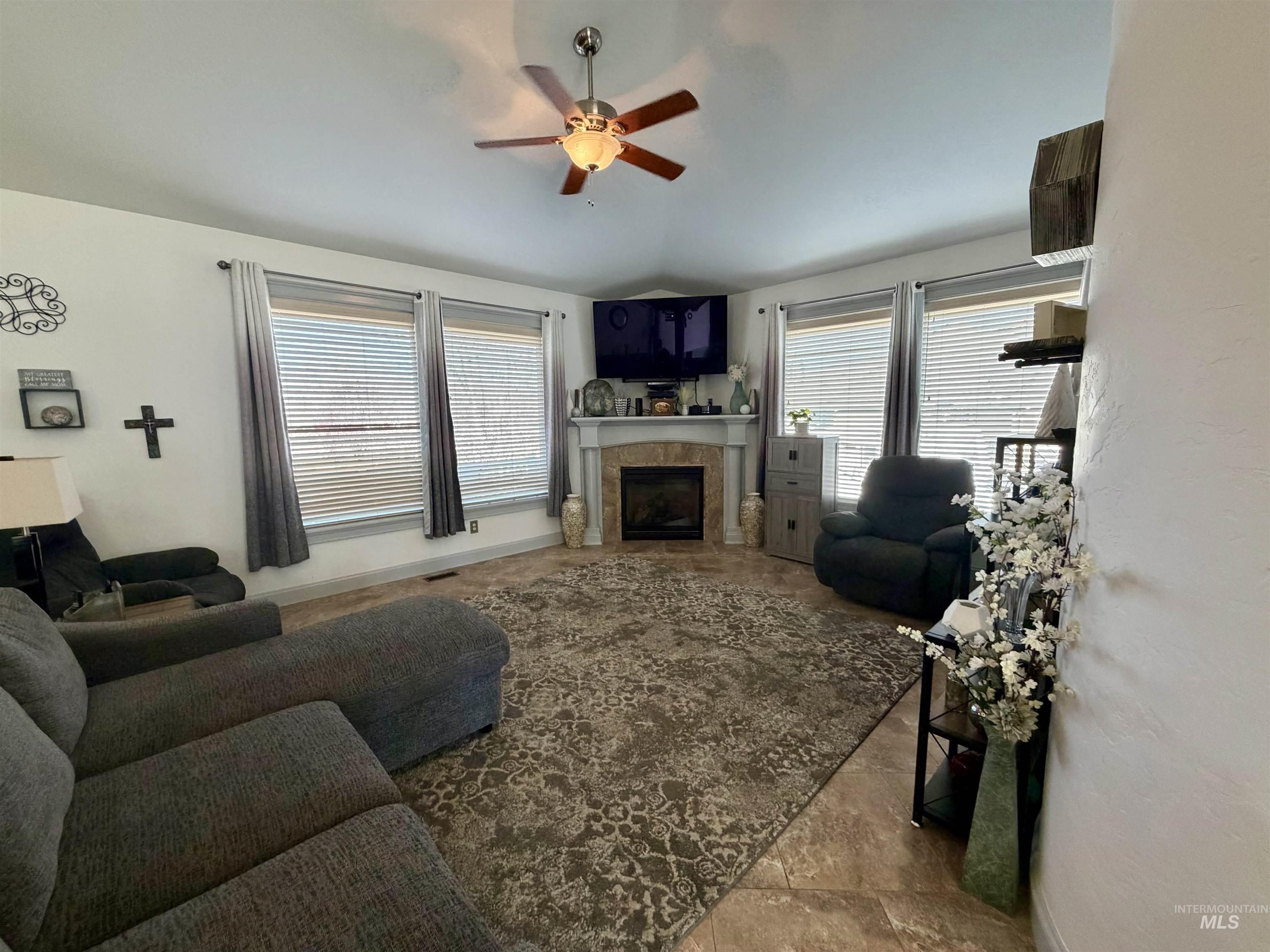 Living room featuring a tiled fireplace, healthy amount of natural light, and a ceiling fan