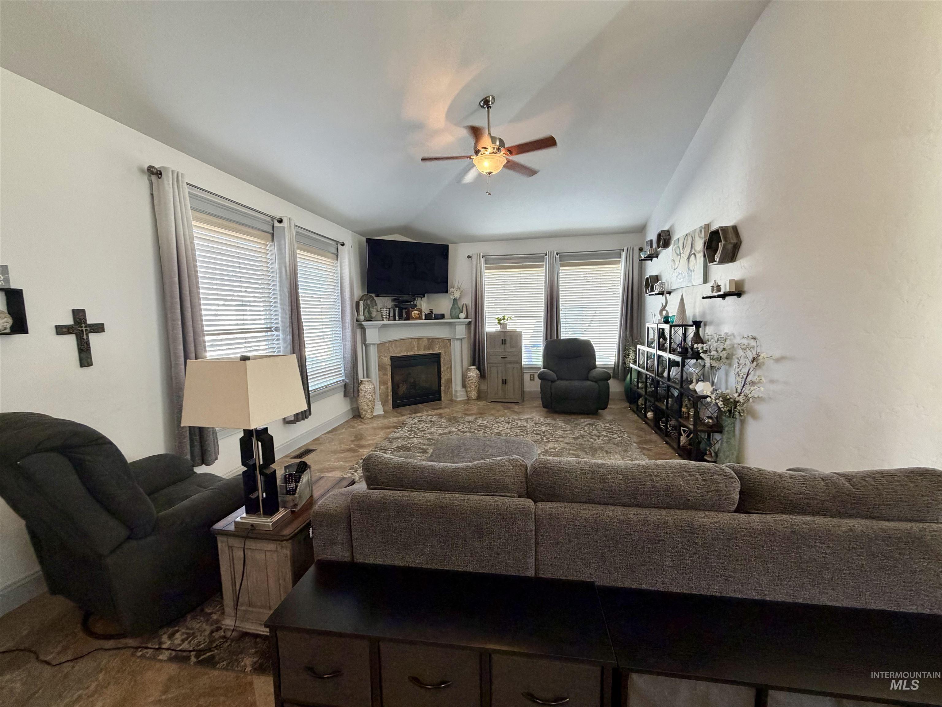 Living area featuring a fireplace, a ceiling fan, and vaulted ceiling