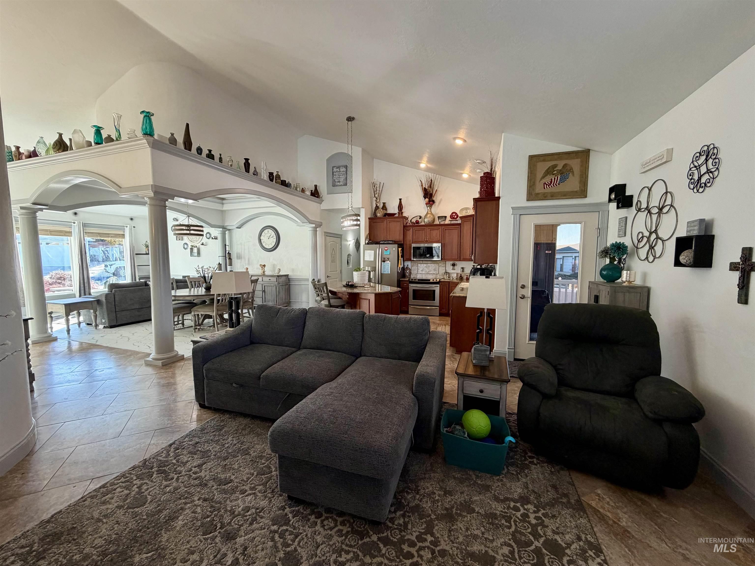 Living area featuring decorative columns, healthy amount of natural light, arched walkways, and high vaulted ceiling