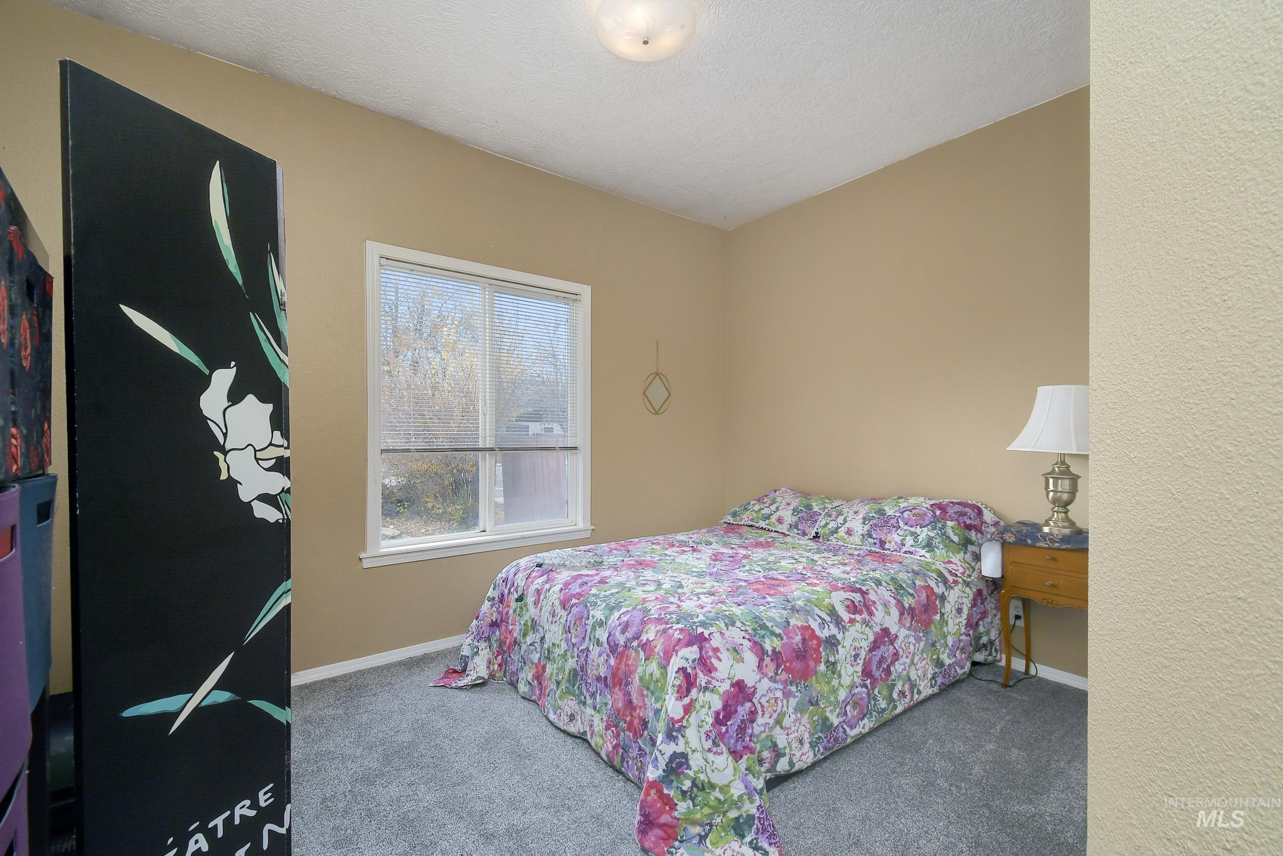 Carpeted bedroom with a textured ceiling and baseboards