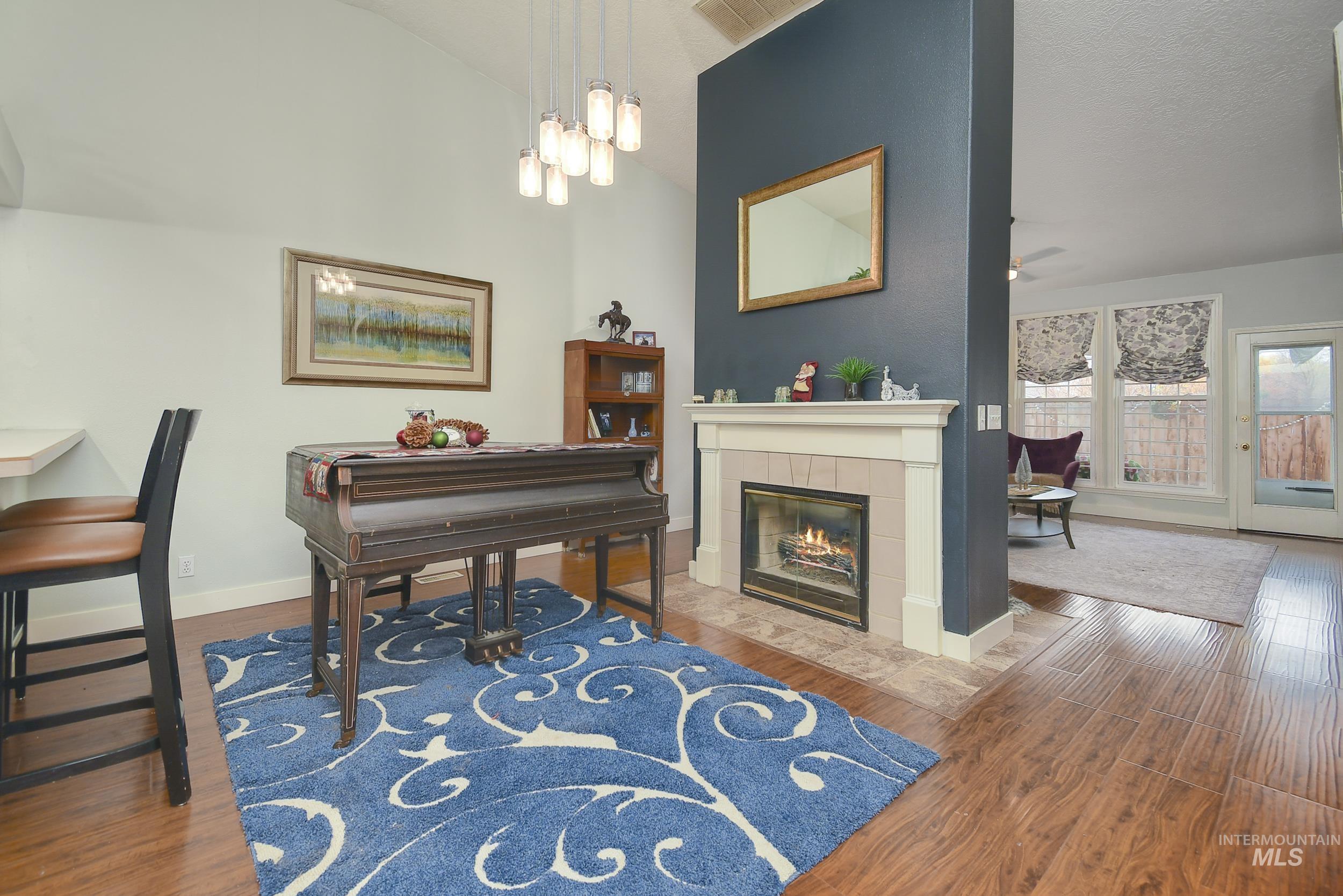 Sitting room featuring dark wood-style floors, lofted ceiling, a fireplace, and ceiling fan