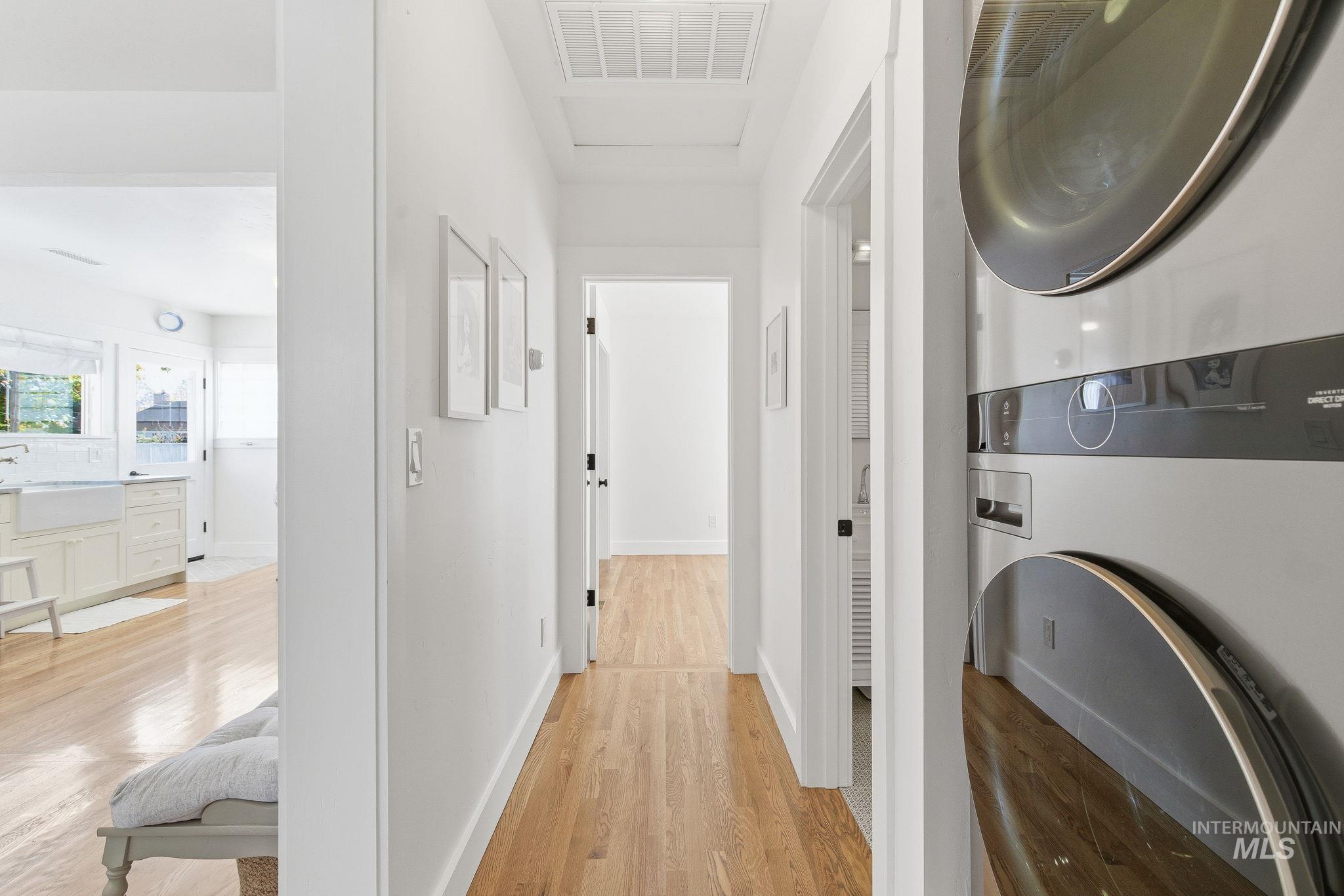 Hallway with light wood-style floors and stacked washing machine and dryer