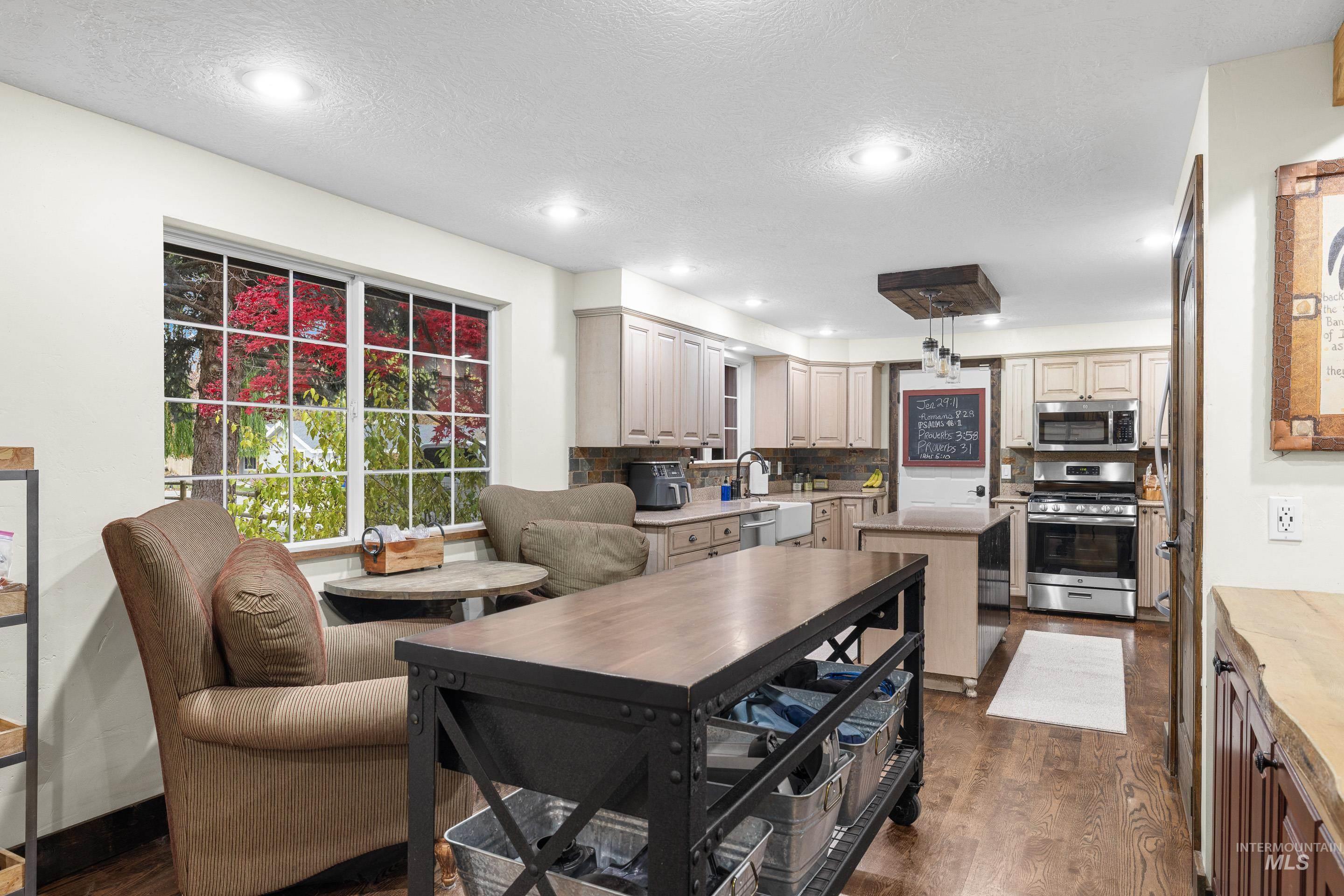Kitchen featuring appliances with stainless steel finishes, a textured ceiling, a center island, dark wood finished floors, and recessed lighting