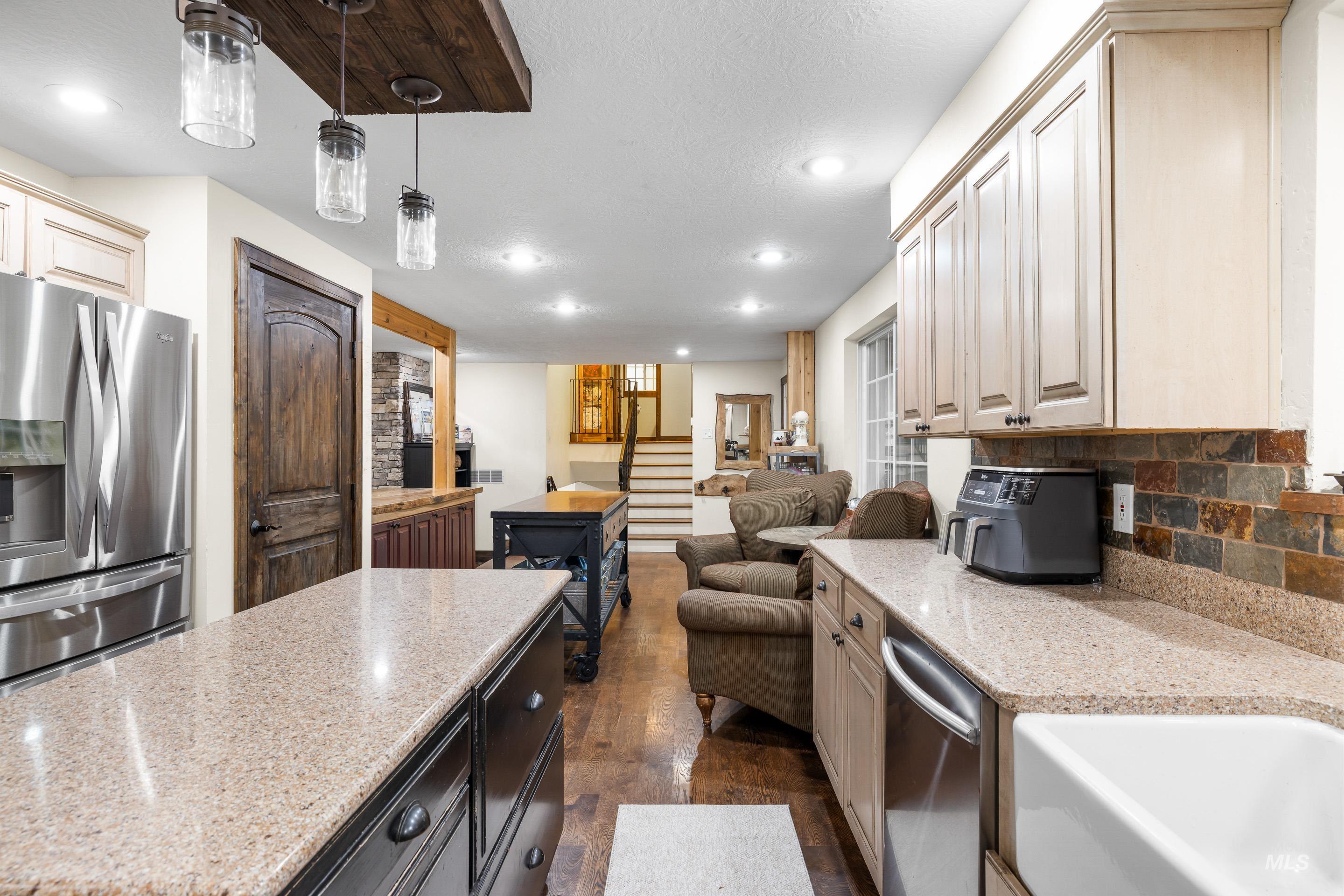 Kitchen with stainless steel appliances, light stone countertops, open floor plan, recessed lighting, and pendant lighting