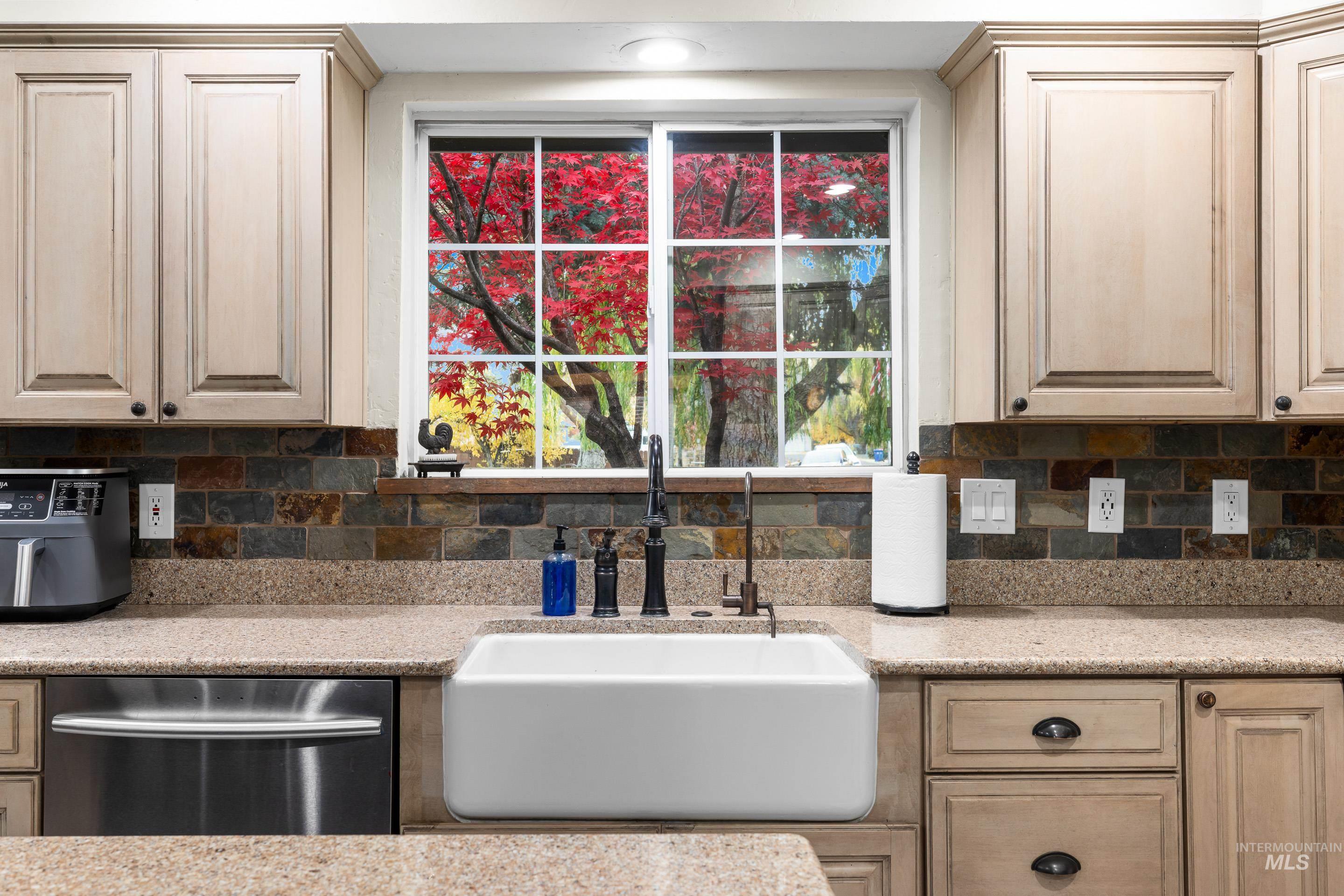Kitchen featuring dishwasher, light stone counters, and tasteful backsplash
