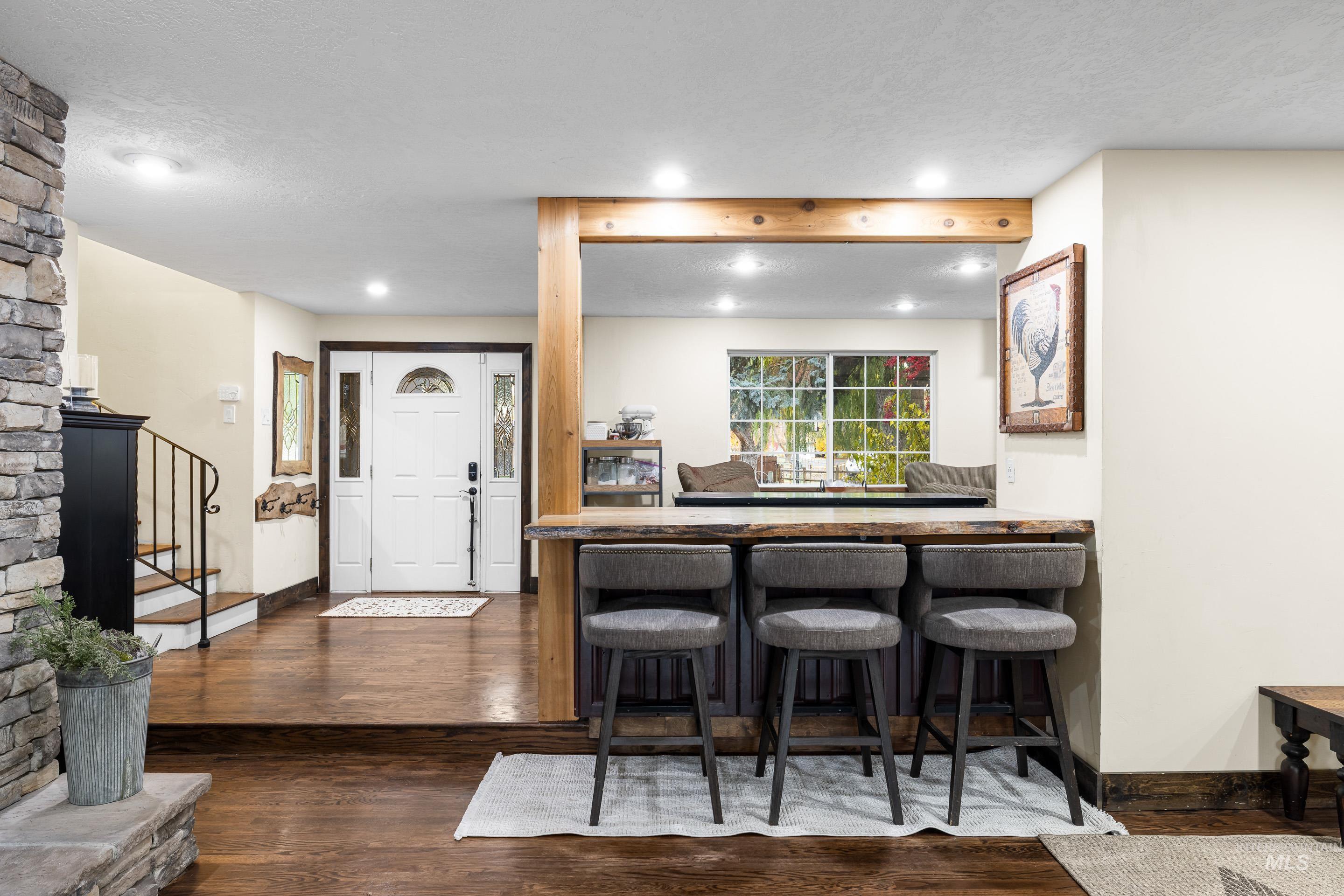 Indoor wet bar with dark wood finished floors, recessed lighting, stairs, and wood counters
