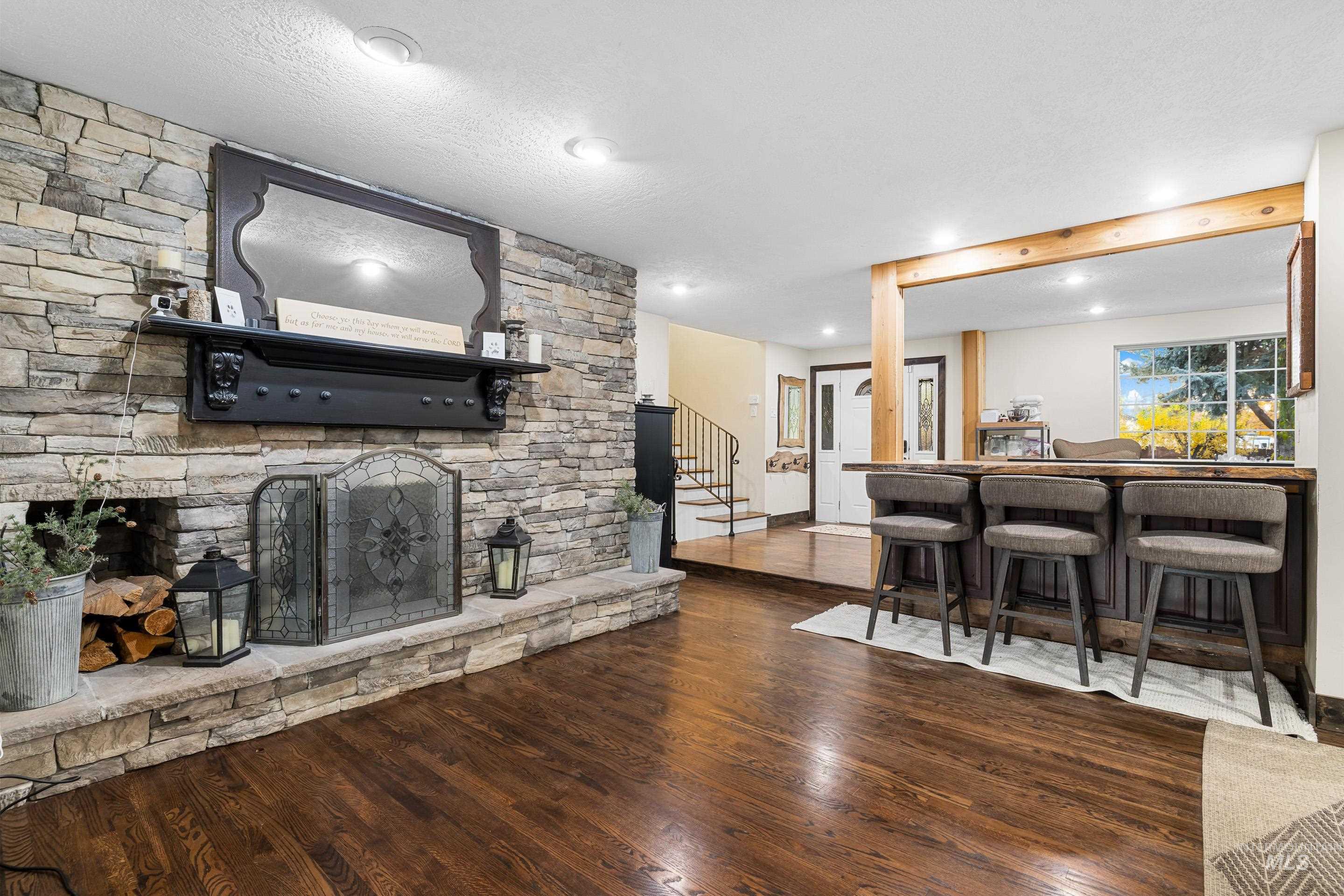 Living room featuring stairway, dark wood finished floors, a fireplace, bar, and recessed lighting