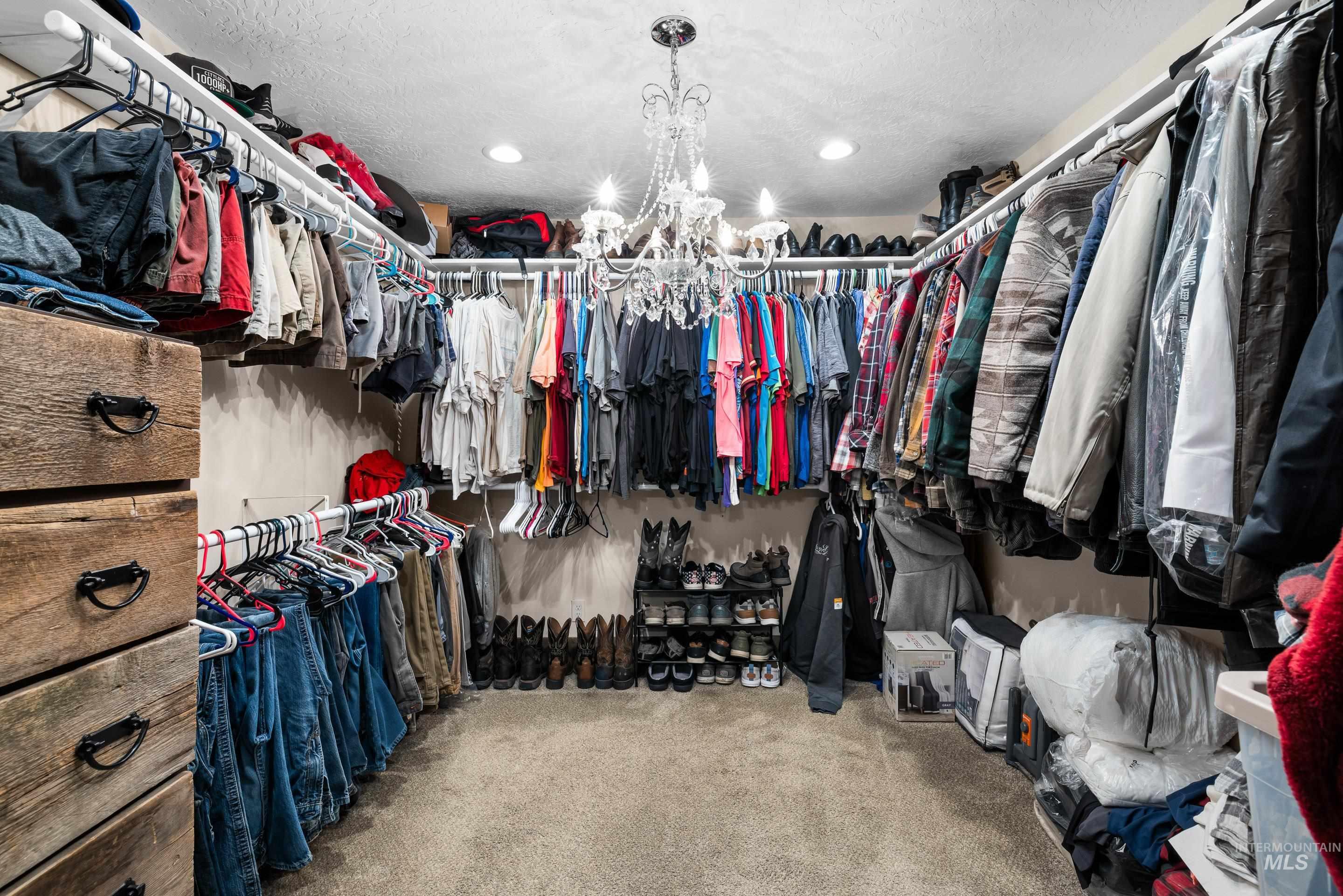 Spacious closet featuring light colored carpet and a chandelier