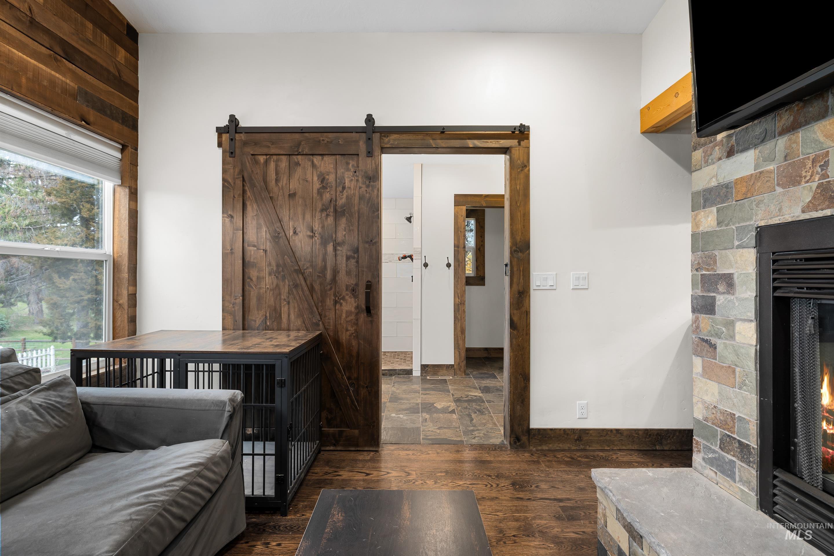 Living room with a fireplace, dark wood-type flooring, and a barn door