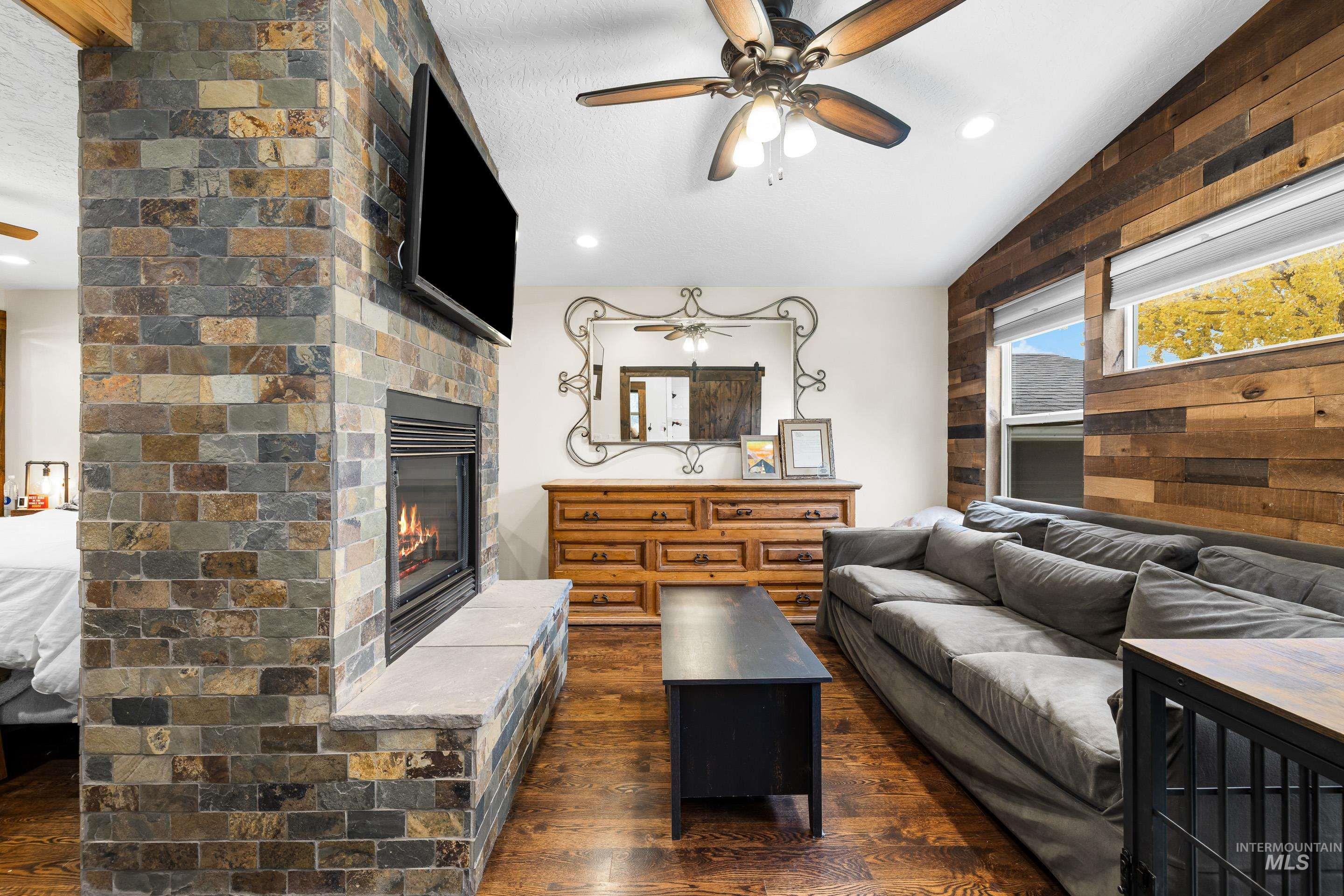 Living room featuring a ceiling fan, dark wood finished floors, a fireplace, lofted ceiling, and recessed lighting