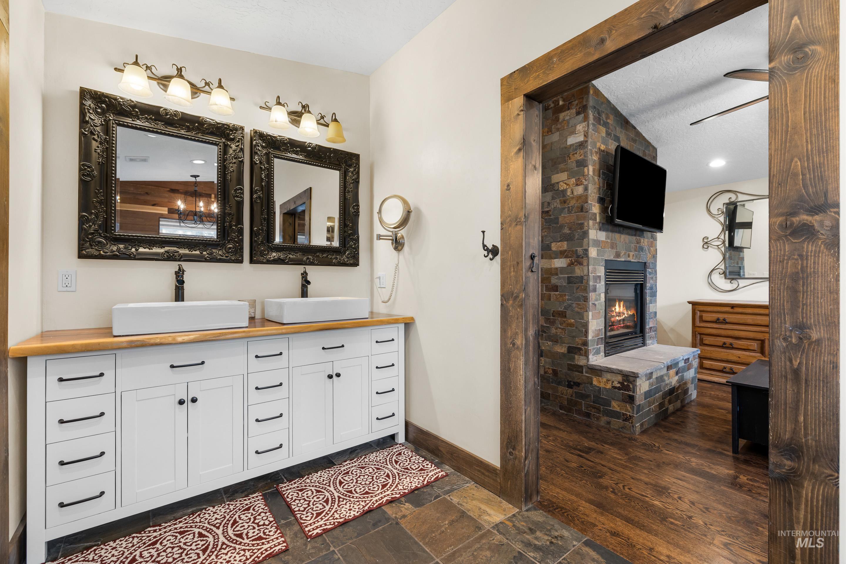 Bathroom featuring double vanity, a fireplace, and stone tile flooring