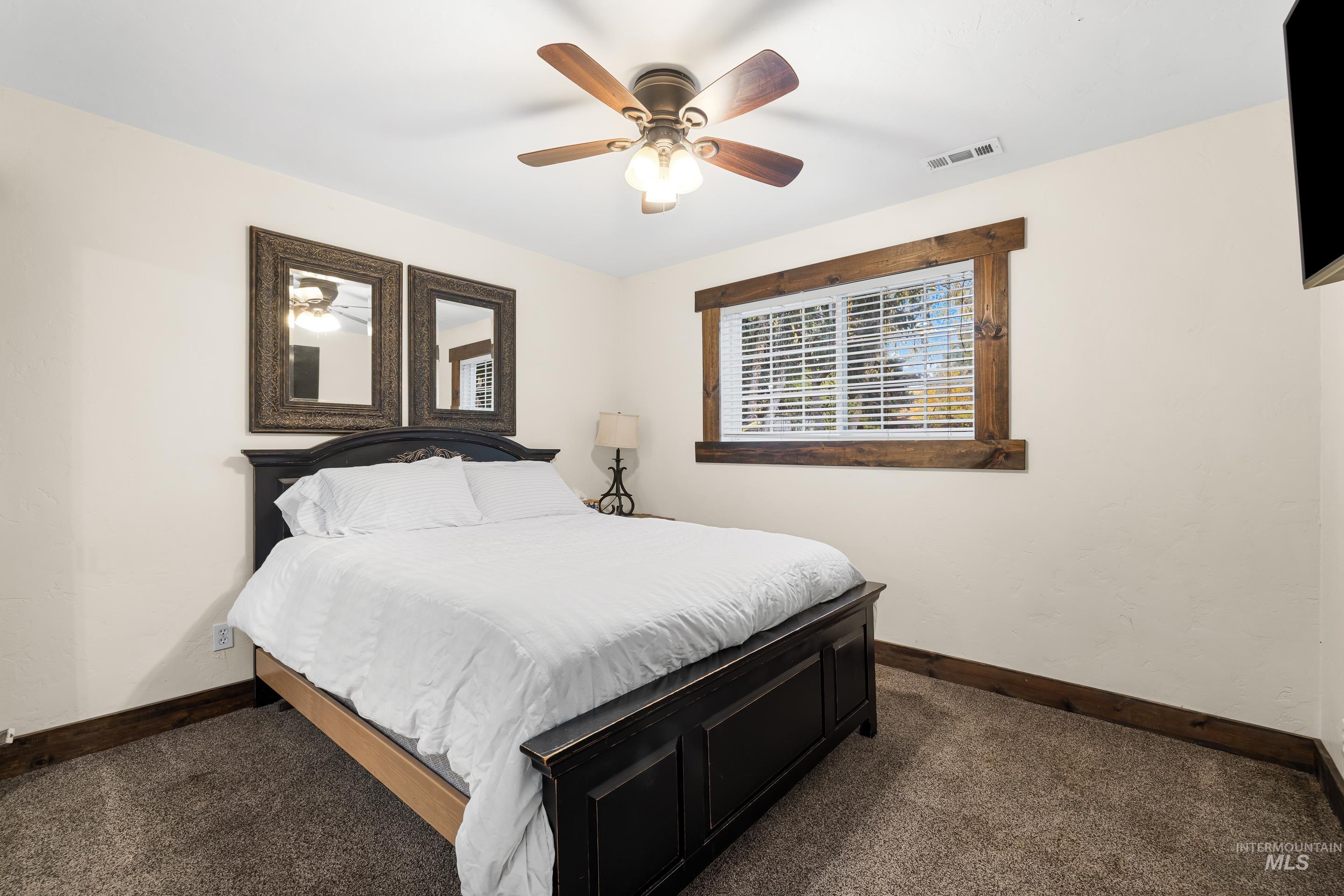 Bedroom featuring dark carpet and a ceiling fan