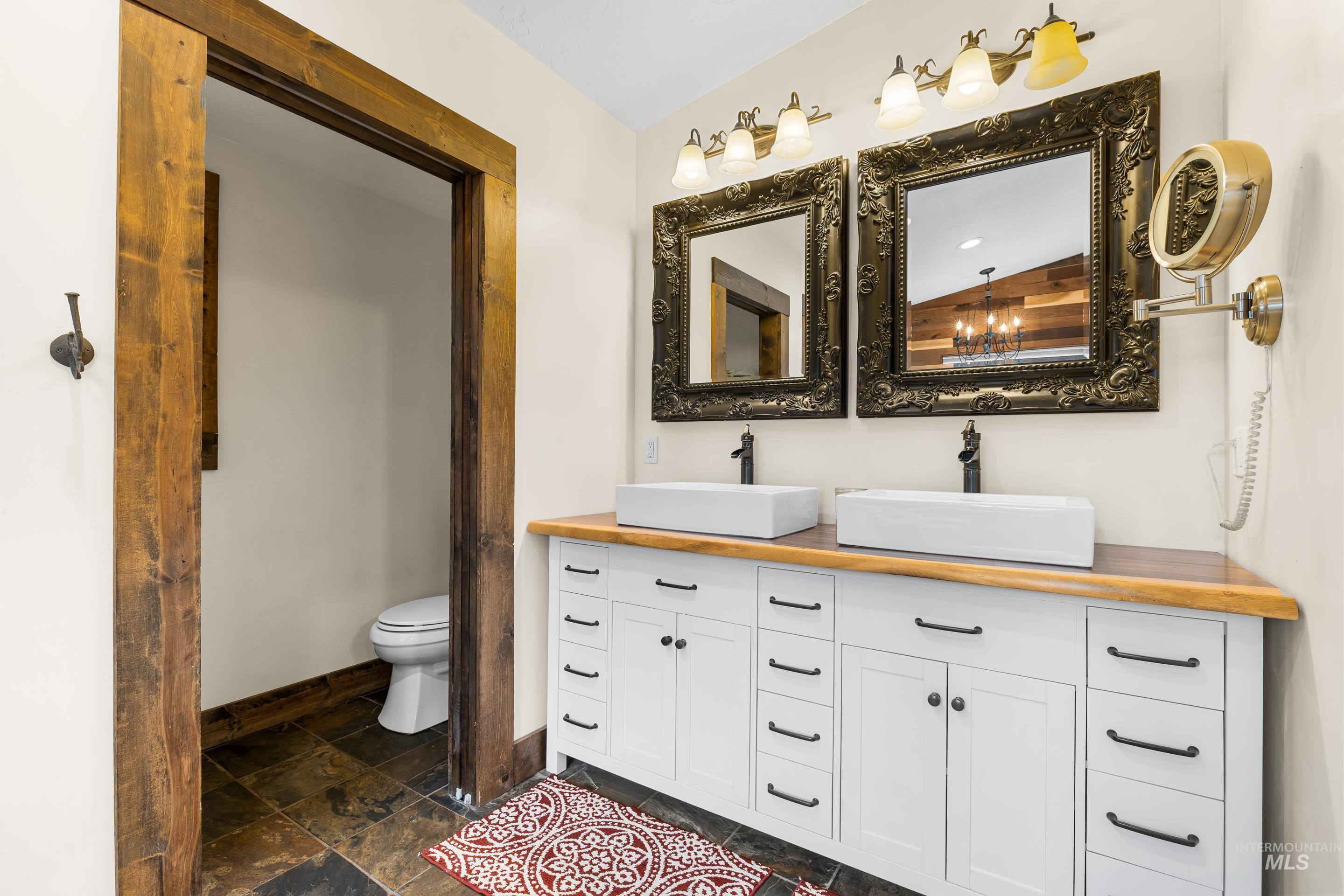 Full bath featuring double vanity and stone tile floors