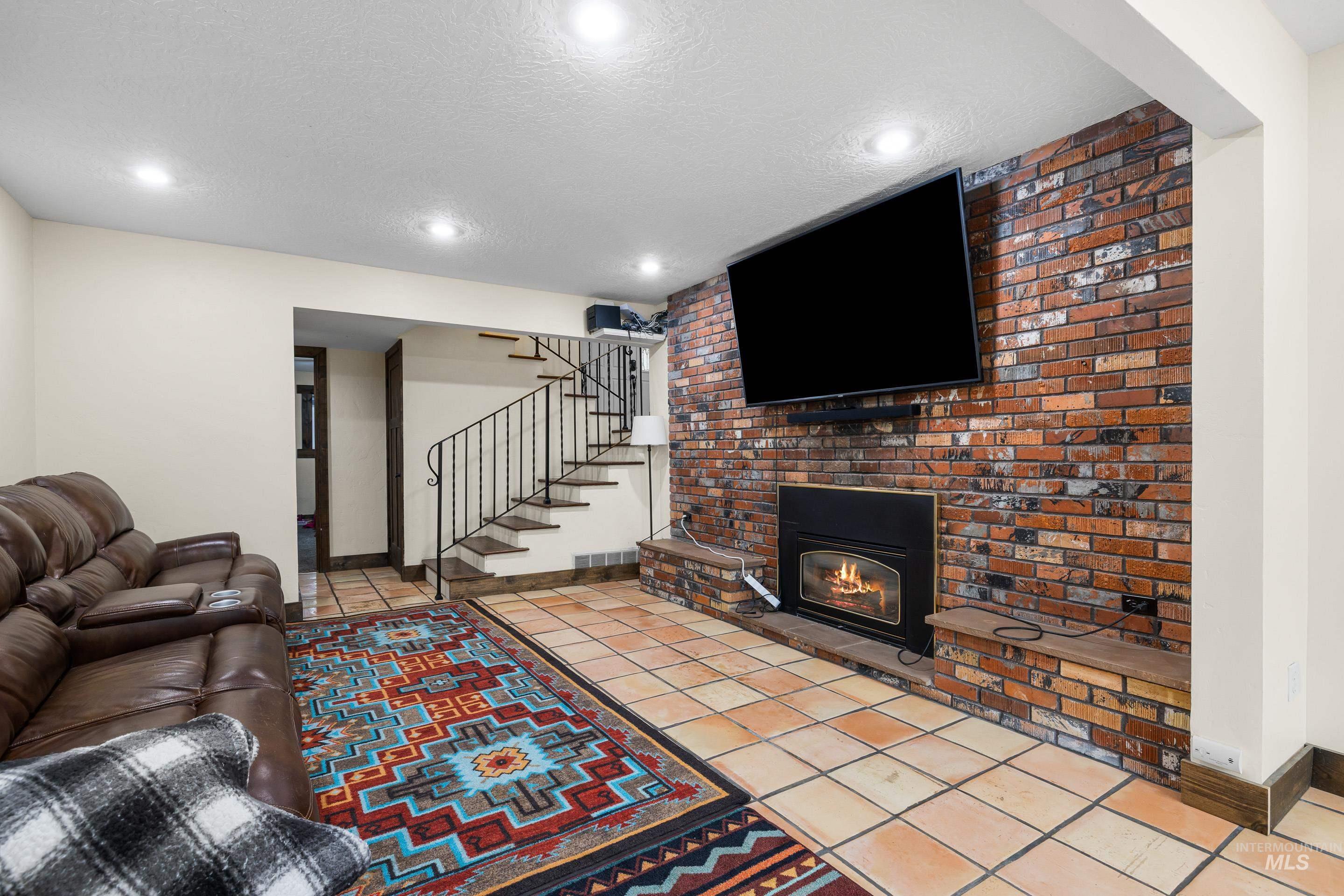 Living room with light tile patterned floors, a textured ceiling, stairs, recessed lighting, and a fireplace