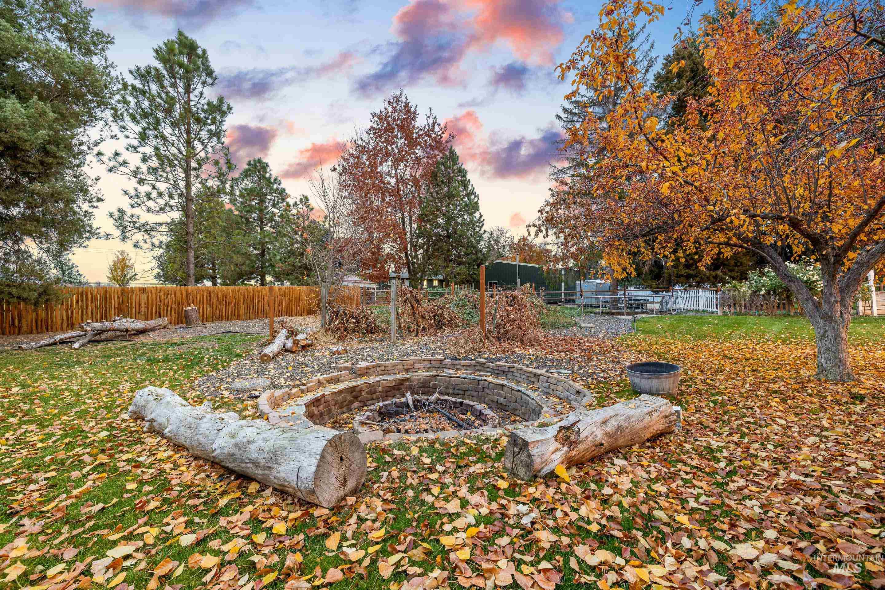 Yard at dusk with a fenced backyard and a fire pit