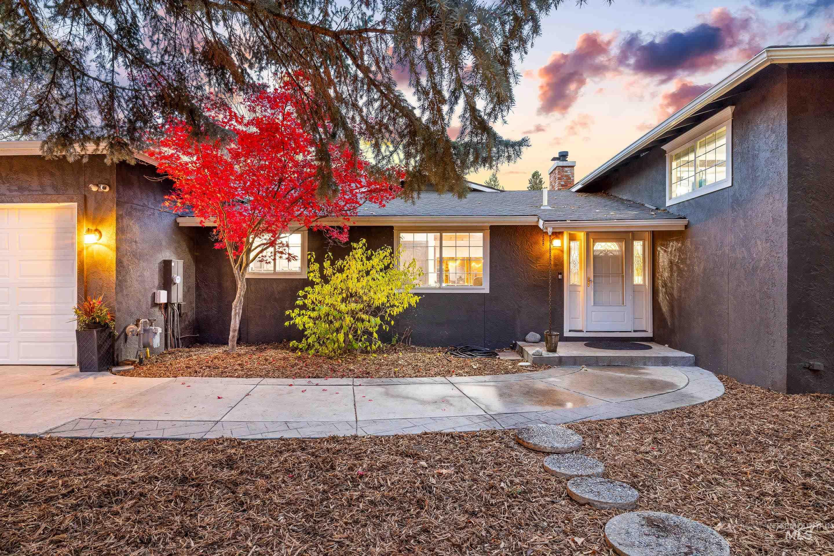View of front facade featuring a chimney, stucco siding, and an attached garage