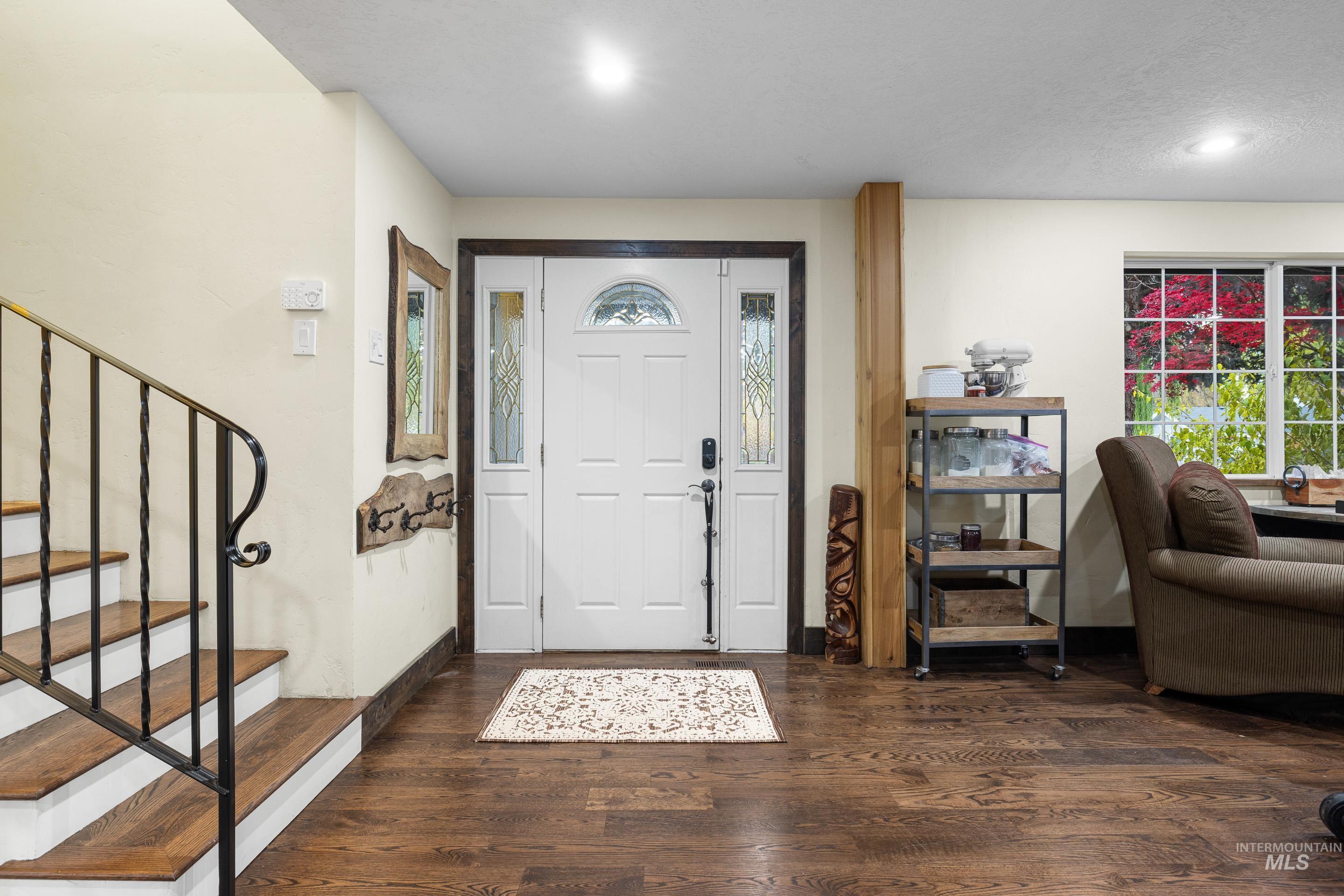 Foyer featuring dark wood-style flooring, healthy amount of natural light, and stairs