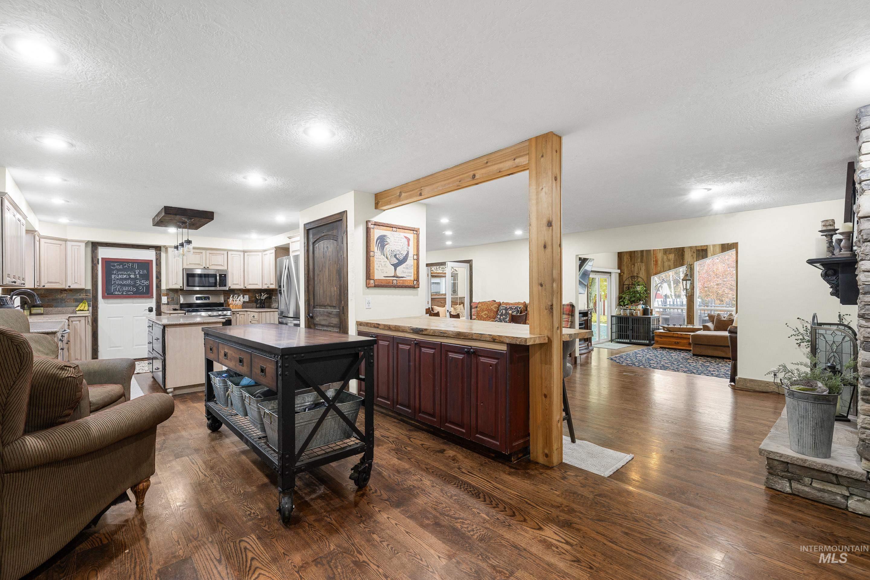 Kitchen with open floor plan, dark wood finished floors, a textured ceiling, stainless steel appliances, and recessed lighting