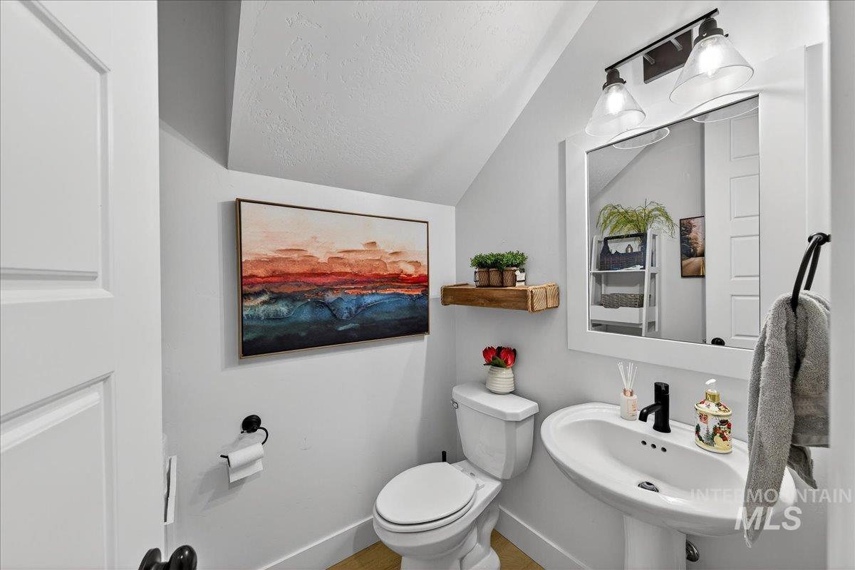 Half bathroom with a textured ceiling and vaulted ceiling