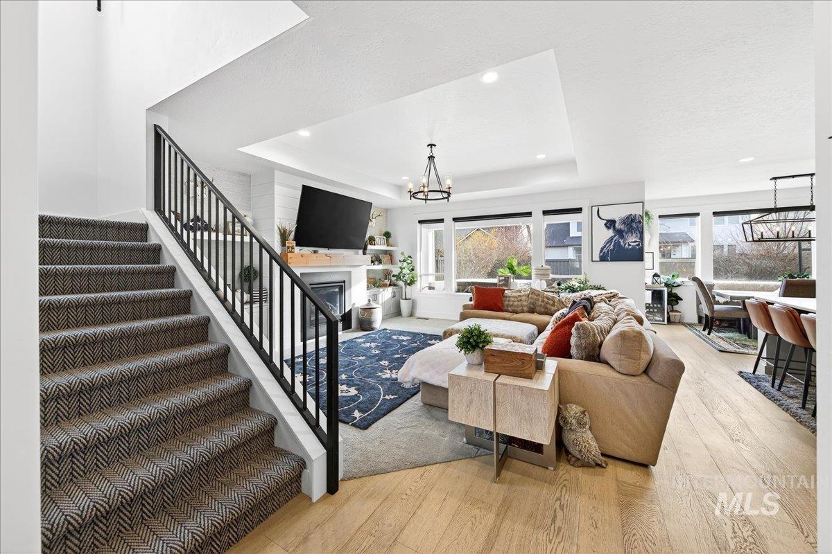 Living room featuring a chandelier, a raised ceiling, light wood-style floors, and recessed lighting