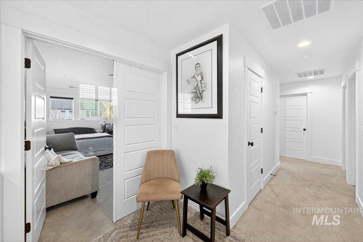 Hallway with light carpet and recessed lighting