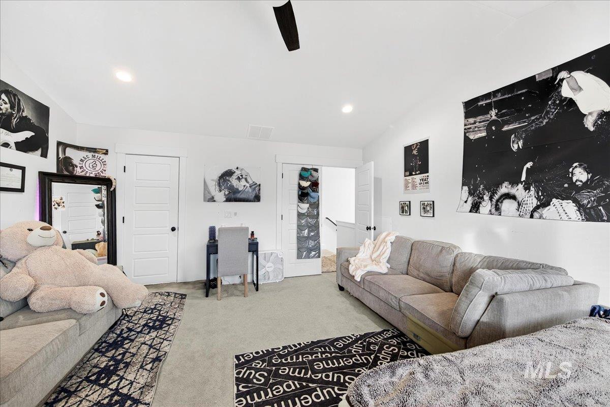 Carpeted living room featuring a ceiling fan, recessed lighting, and vaulted ceiling