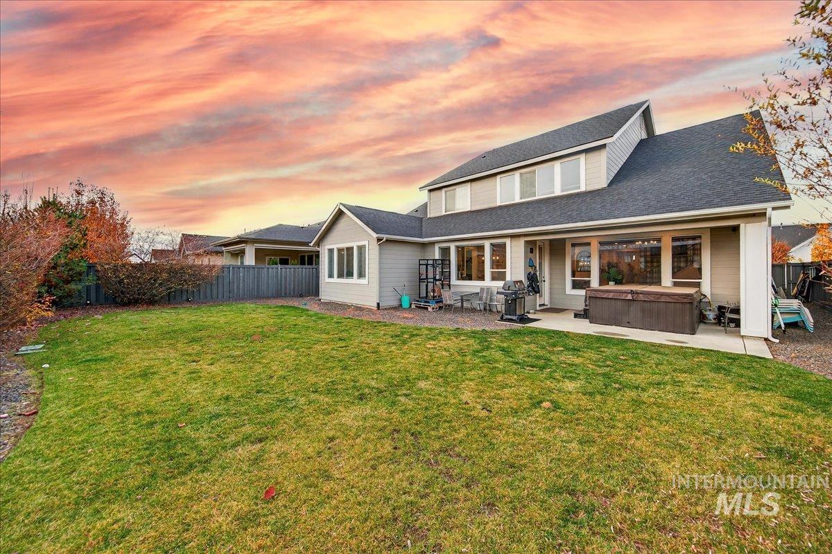 Back of property with a hot tub, a patio area, and roof with shingles