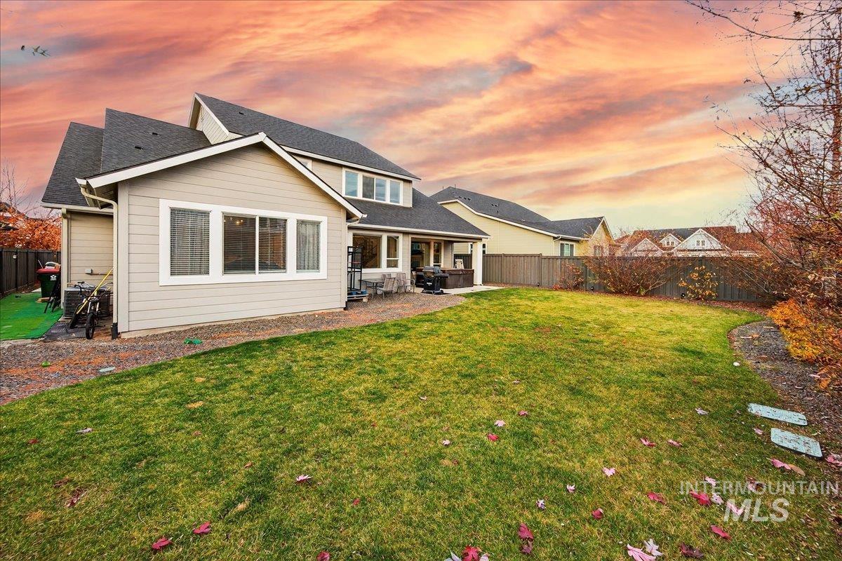 Back of property at dusk featuring a fenced backyard, a patio, and a shingled roof