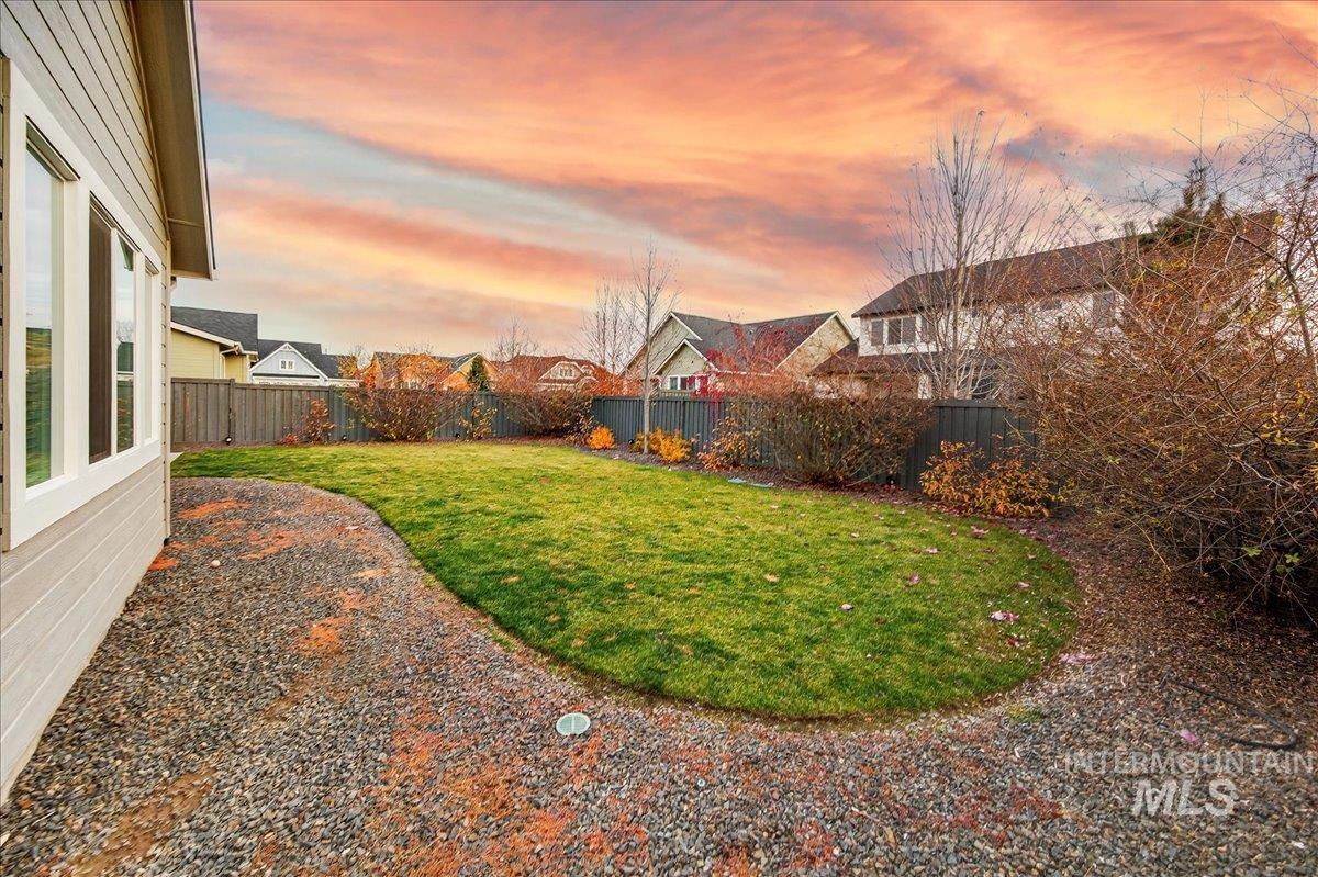 Yard at dusk featuring a fenced backyard and a residential view