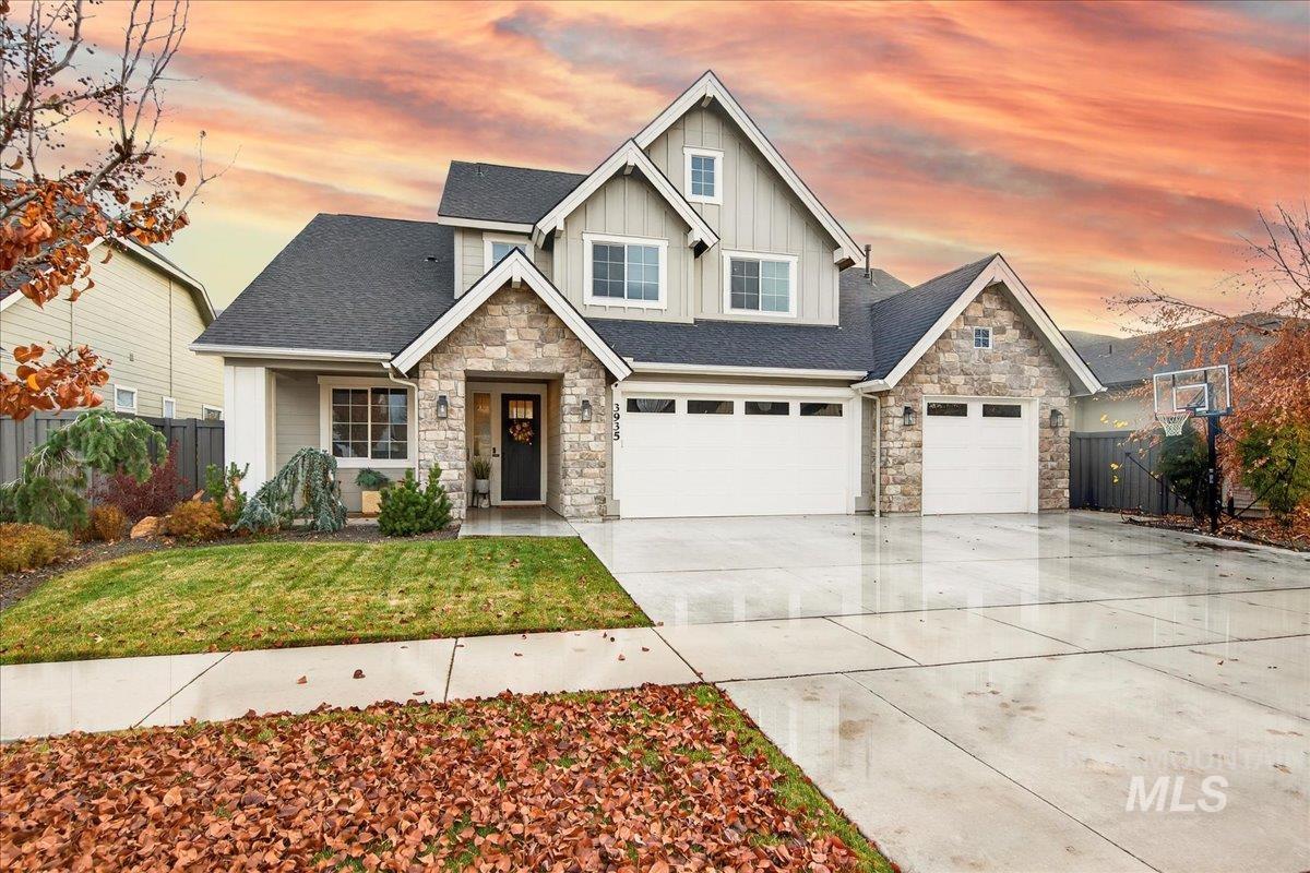 Craftsman inspired home featuring stone siding, board and batten siding, a shingled roof, and driveway