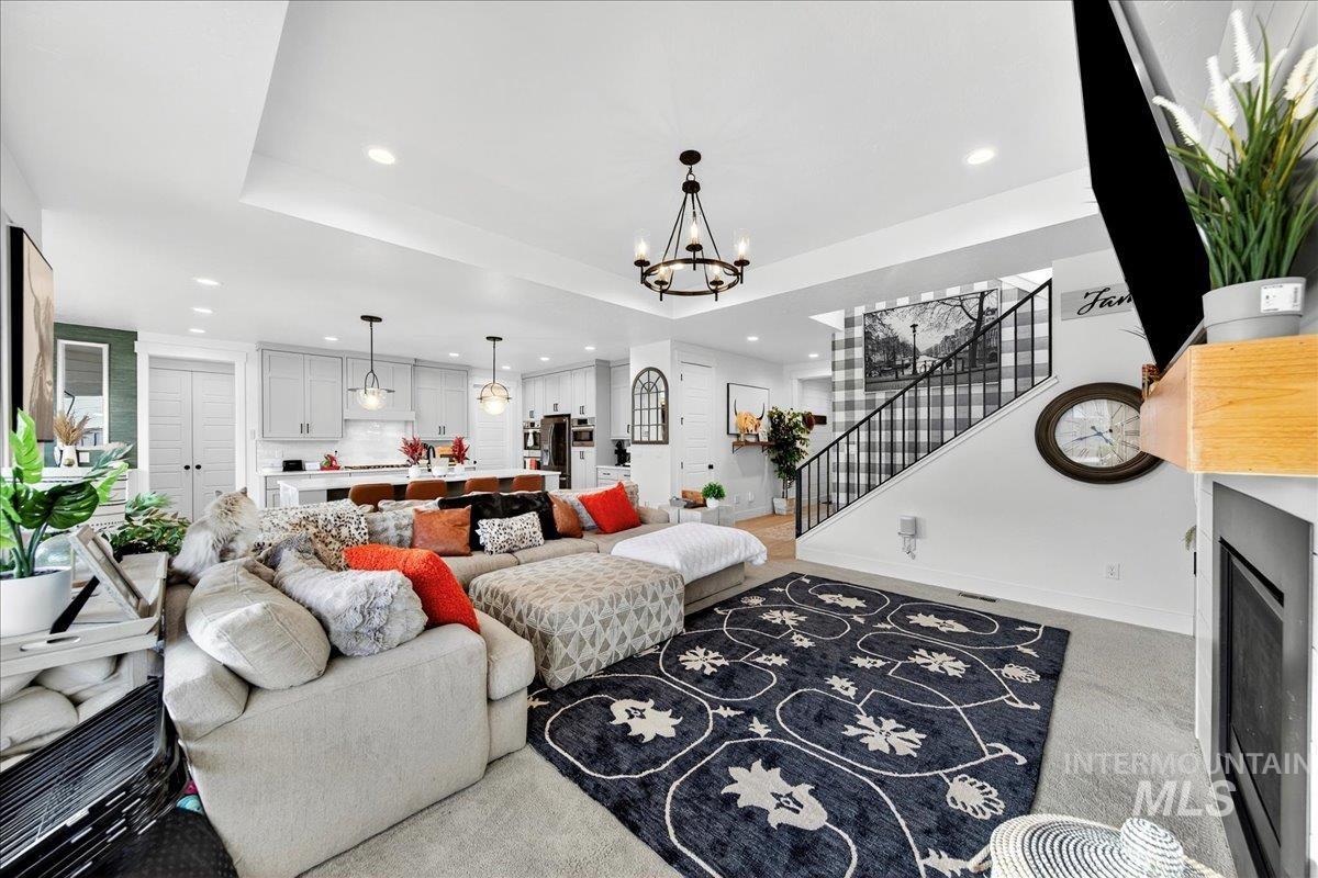 Living room with stairway, recessed lighting, a raised ceiling, carpet flooring, and a fireplace