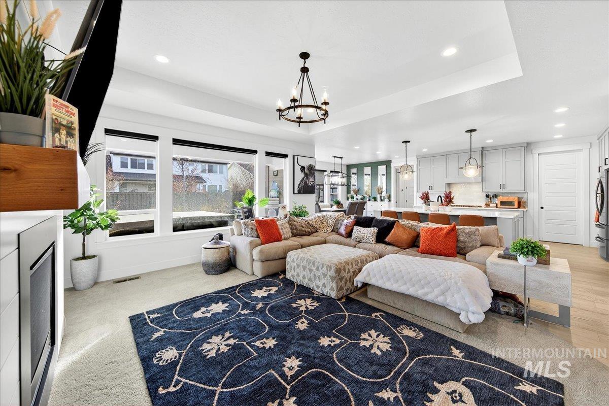 Living area with a raised ceiling, recessed lighting, and a chandelier