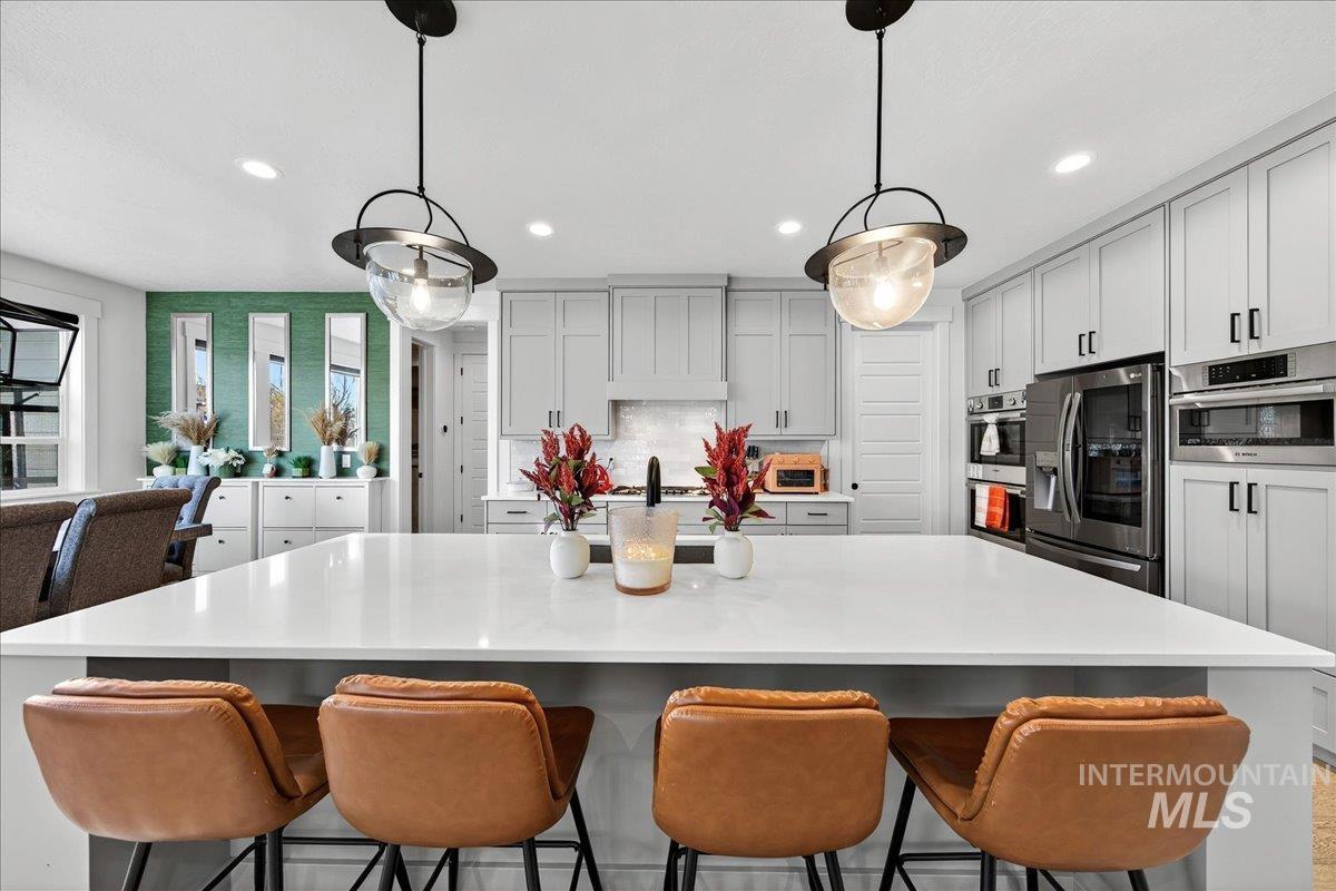 Kitchen featuring appliances with stainless steel finishes, a breakfast bar, tasteful backsplash, a center island, and gray cabinets