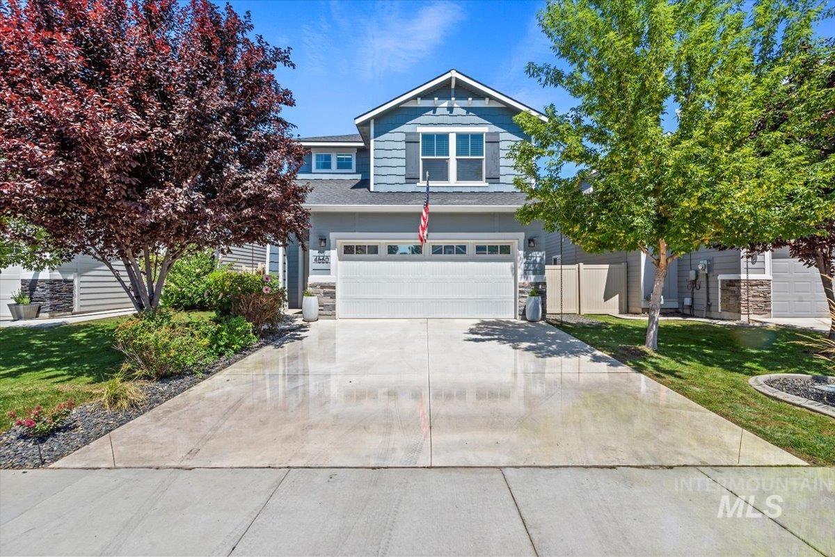 View of front of home featuring a garage, concrete driveway, and stone siding
