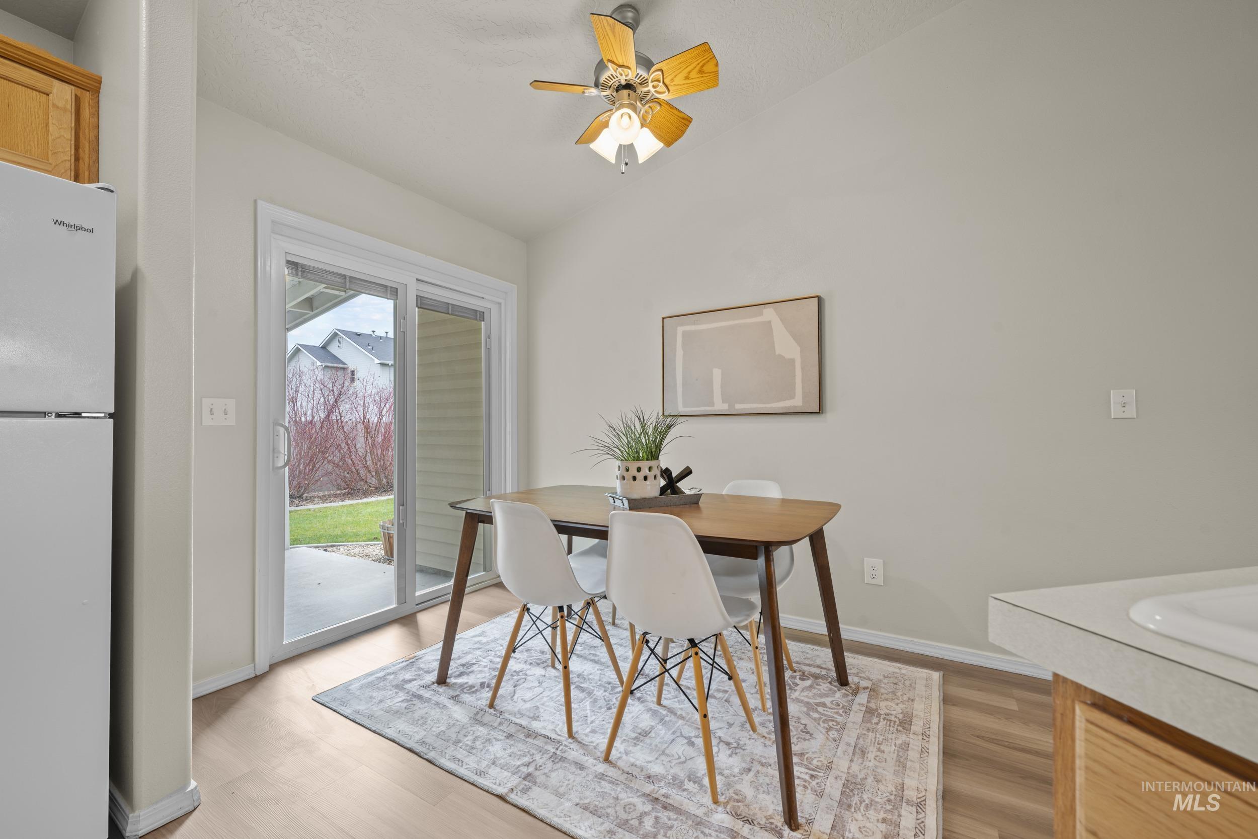 Dining area featuring vaulted ceiling, light wood-type flooring, and a ceiling fan