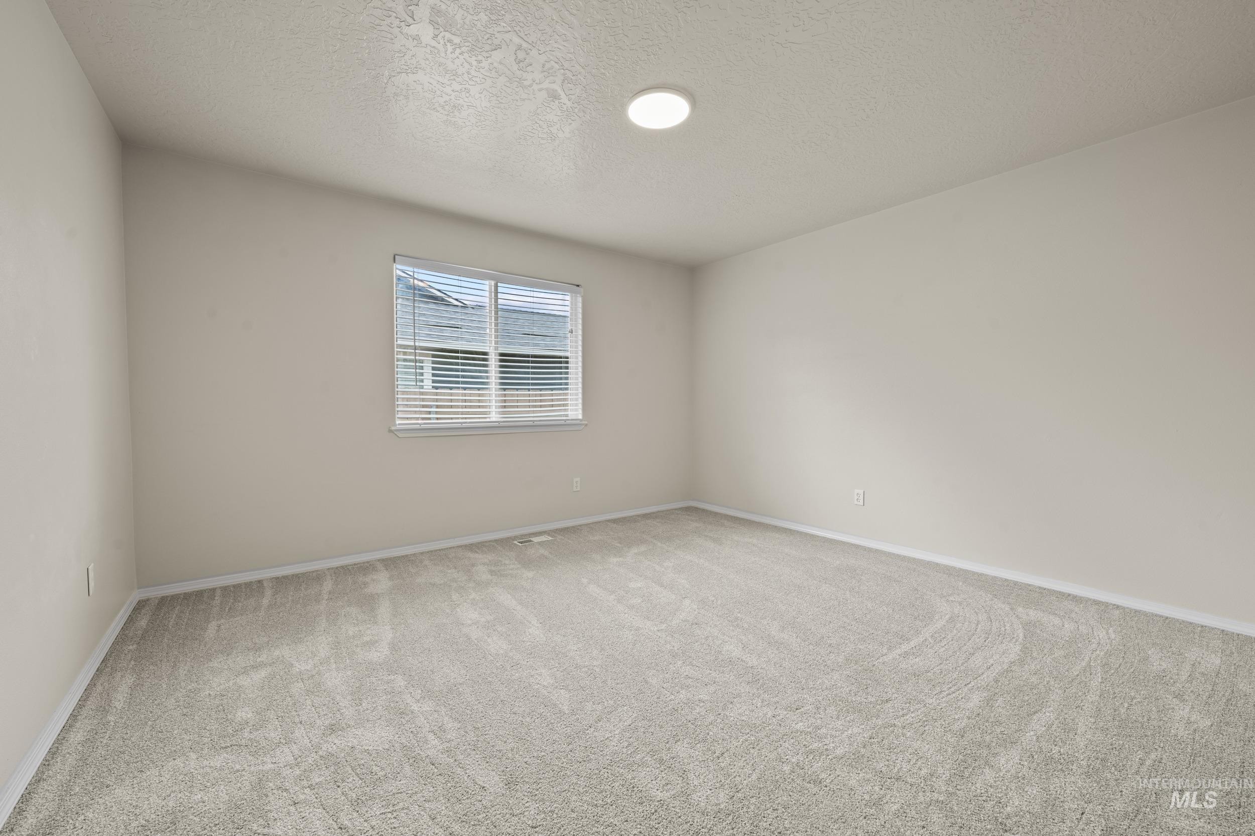 Spare room featuring a textured ceiling and light carpet