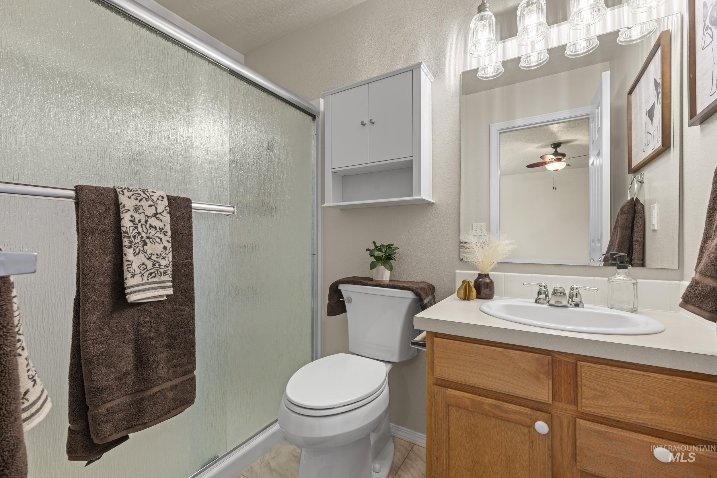 Bathroom with vanity, a shower stall, a ceiling fan, and light tile patterned flooring
