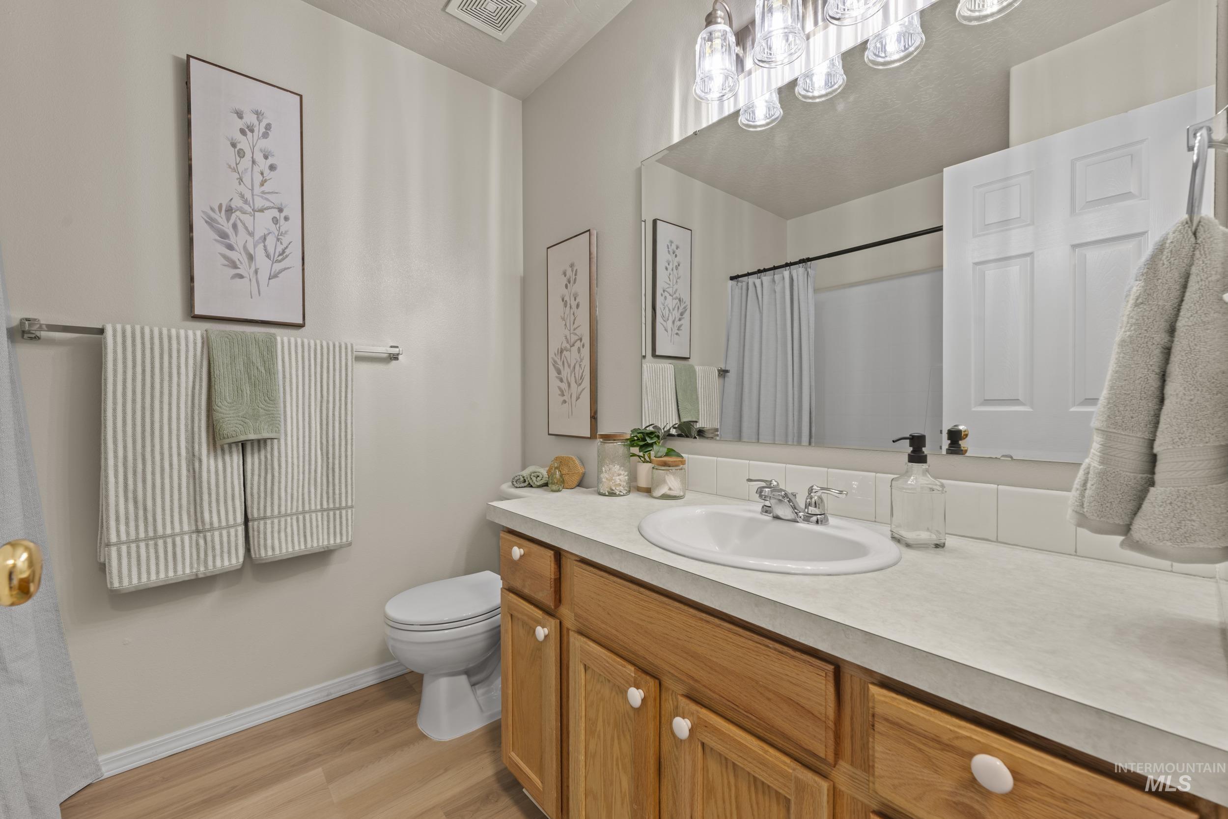 Full bath featuring vanity, light wood finished floors, and a shower with curtain