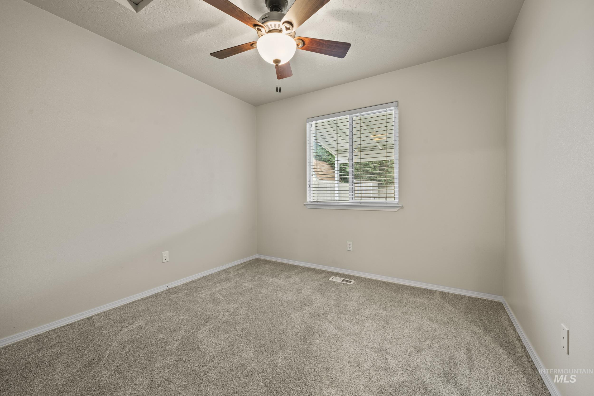 Carpeted empty room featuring a ceiling fan and a textured ceiling