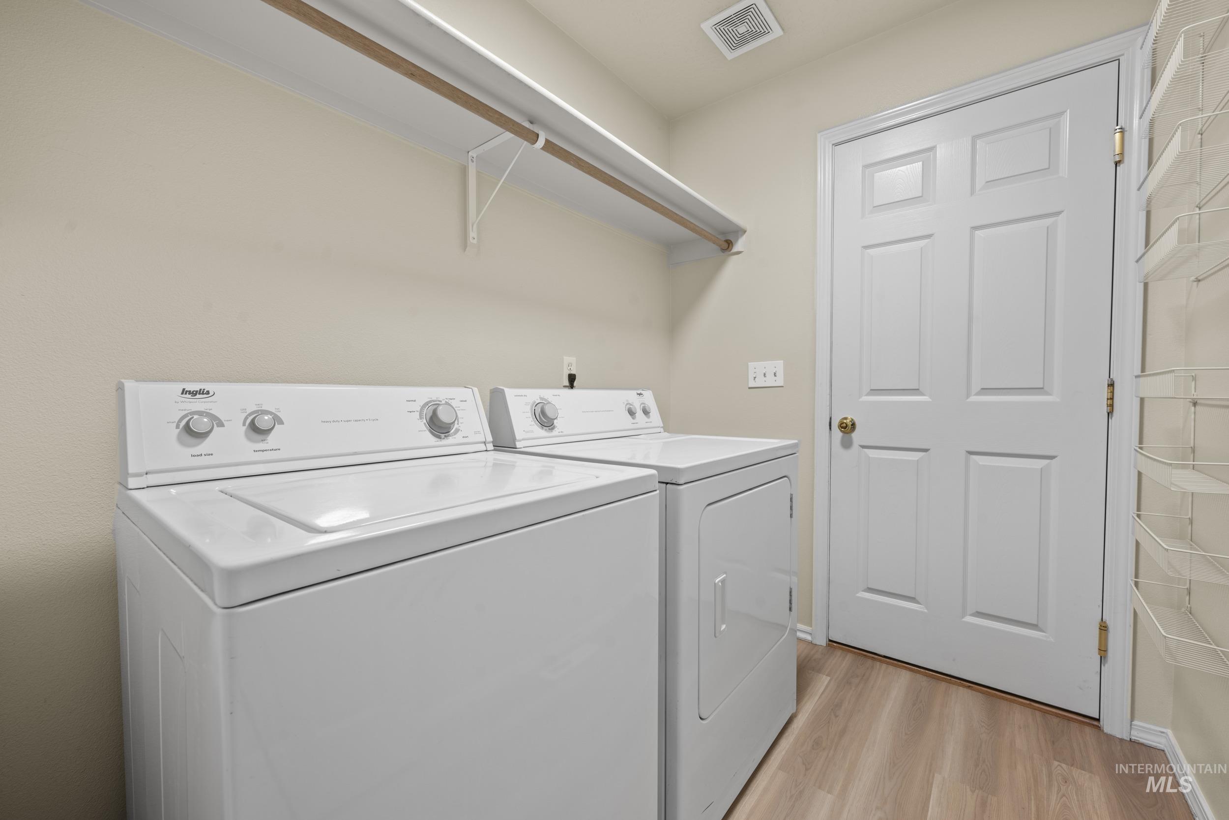 Washroom with light wood-style flooring and independent washer and dryer