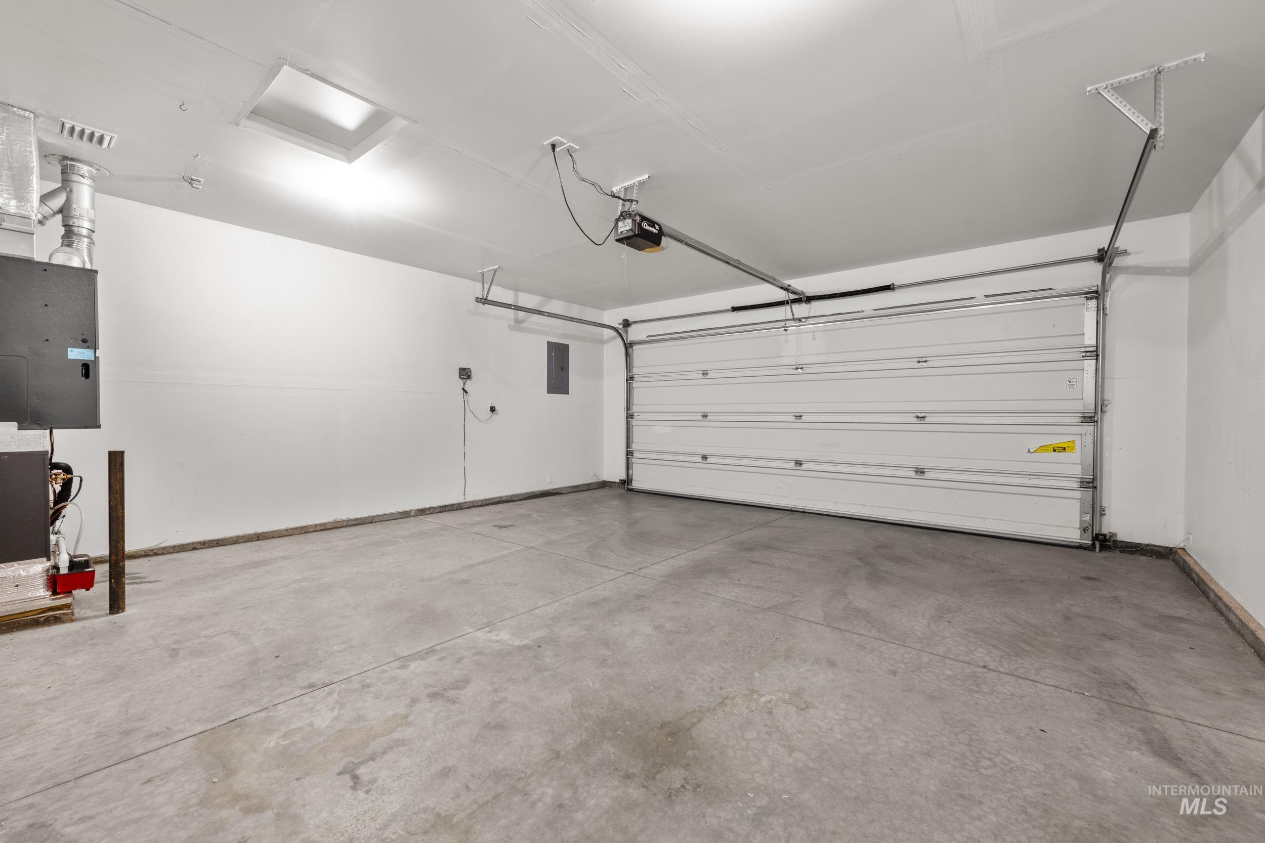 Garage featuring electric panel and a garage door opener