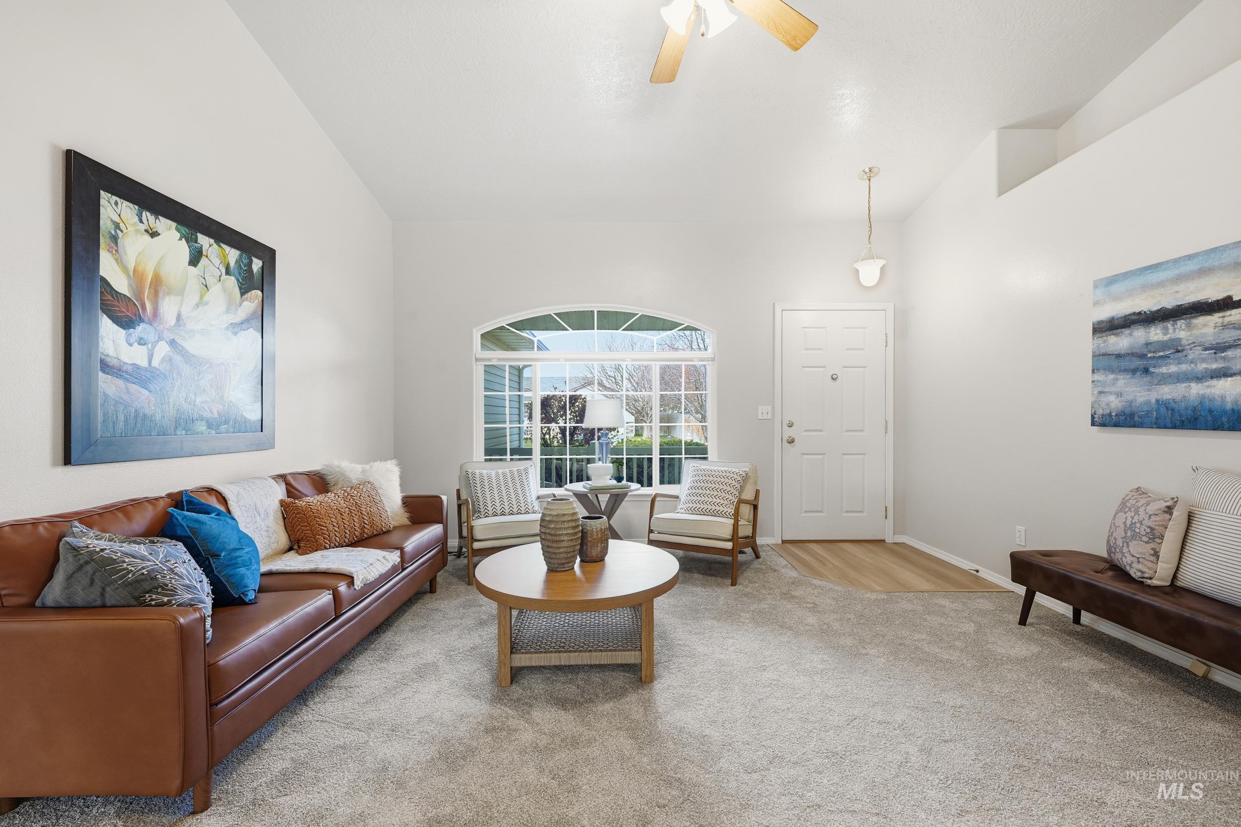 Carpeted living area with a ceiling fan and baseboards