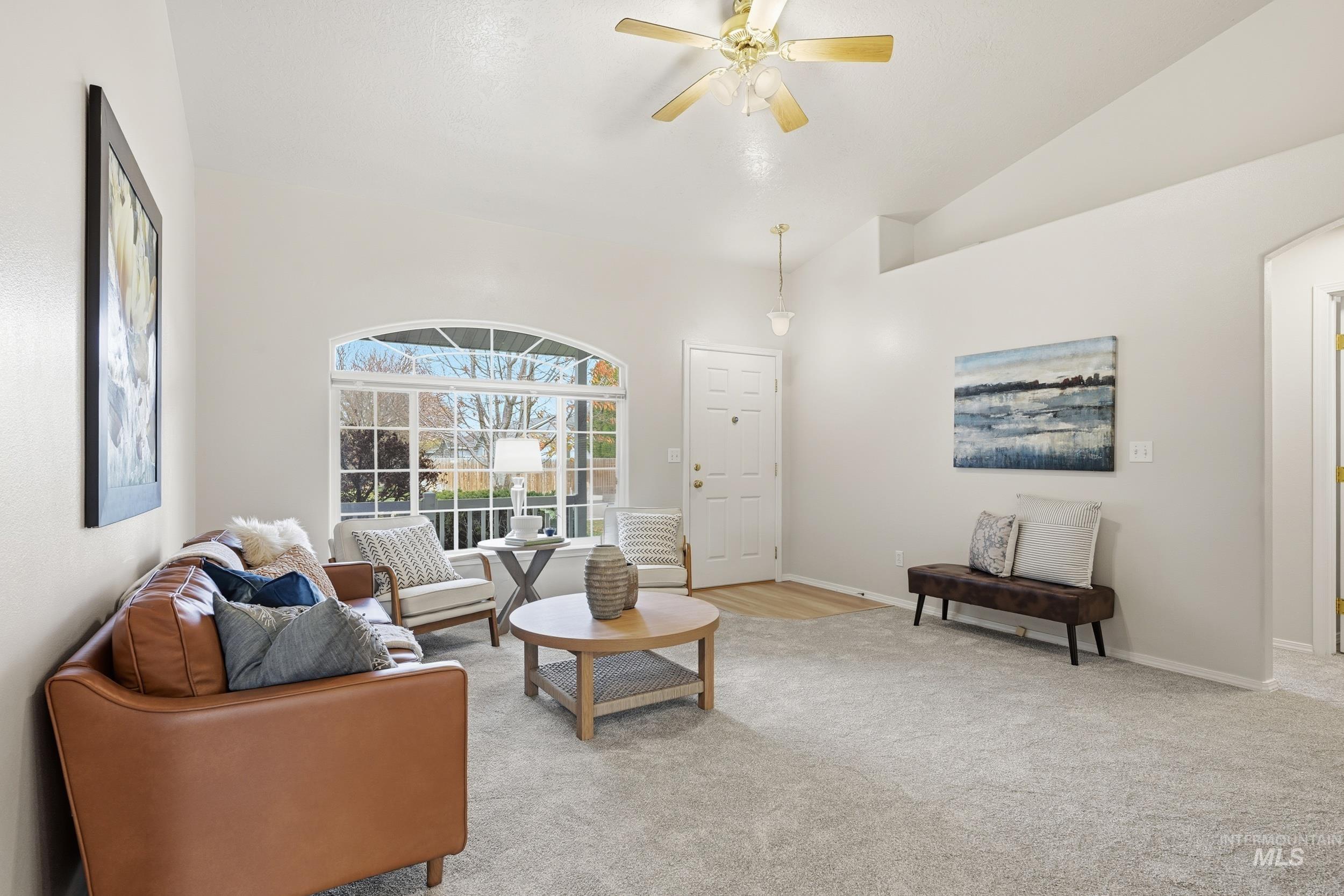 Carpeted living area with lofted ceiling and ceiling fan