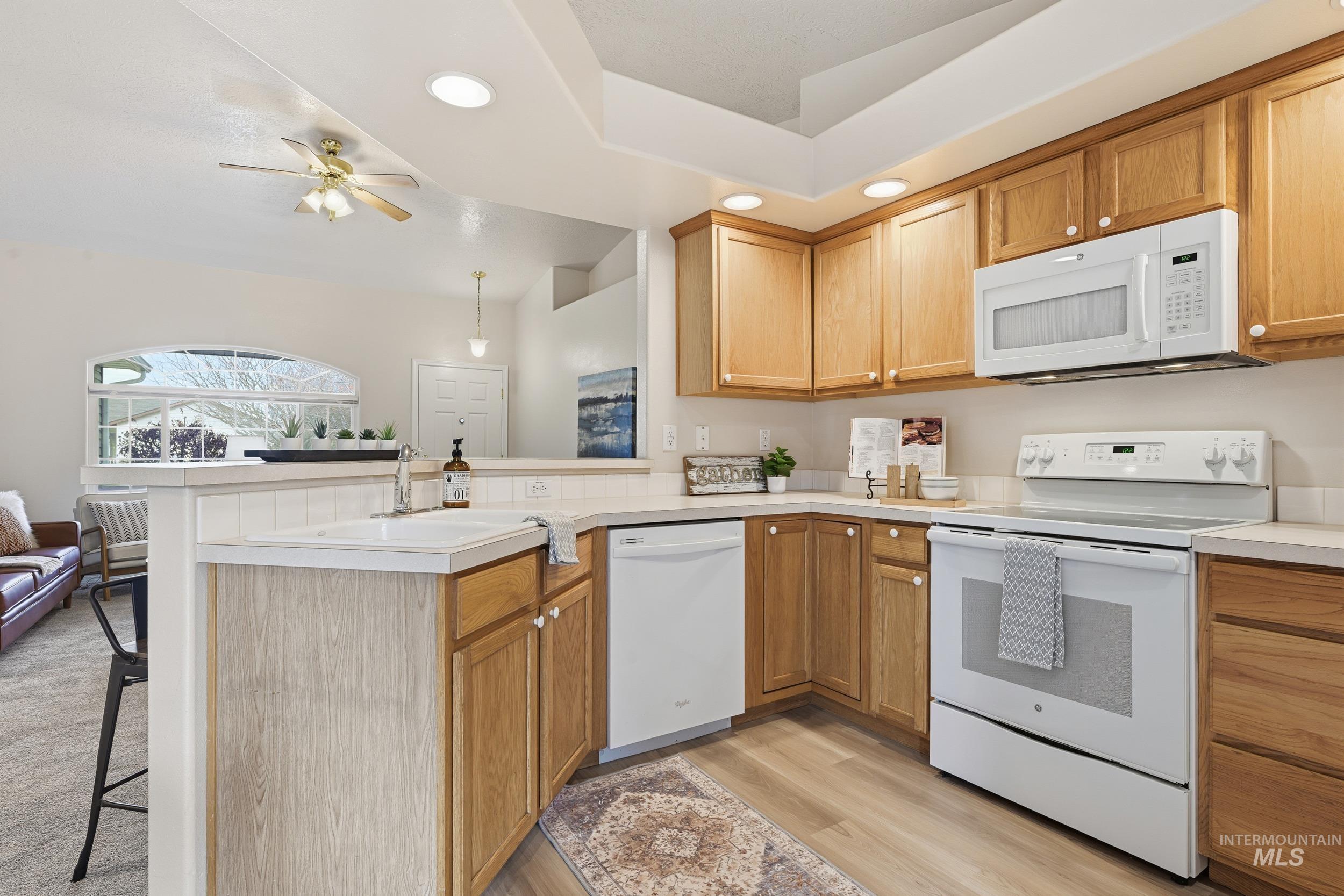 Kitchen featuring white appliances, recessed lighting, a peninsula, light countertops, and light wood-style floors