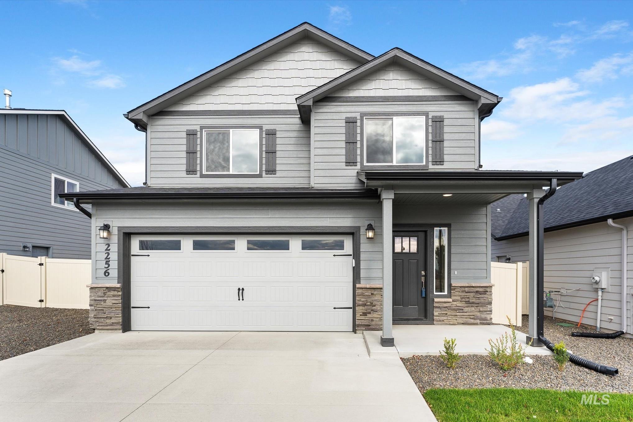 View of front facade with stone siding, a porch, an attached garage, and concrete driveway