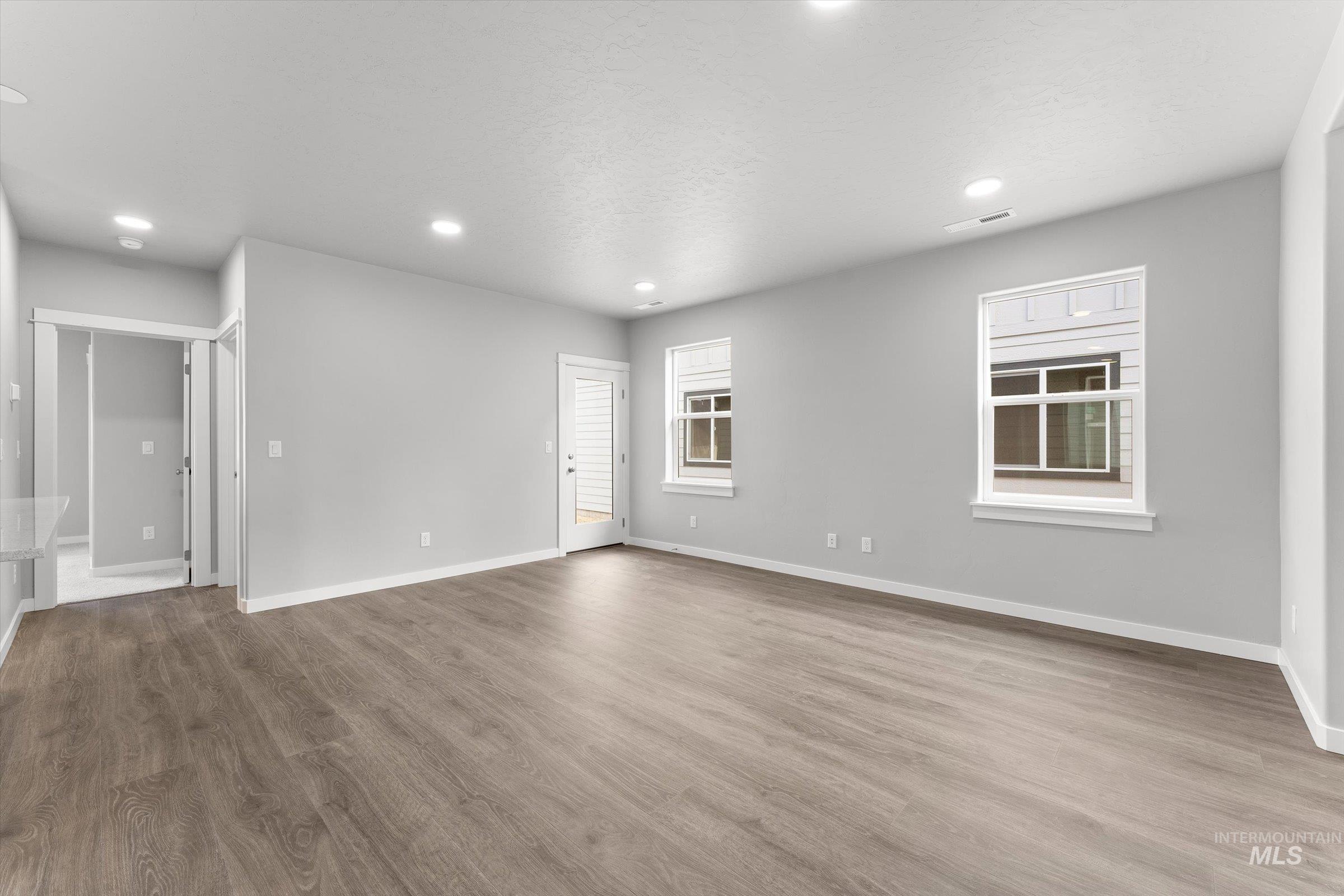 Unfurnished living room with light wood-style floors, healthy amount of natural light, and recessed lighting