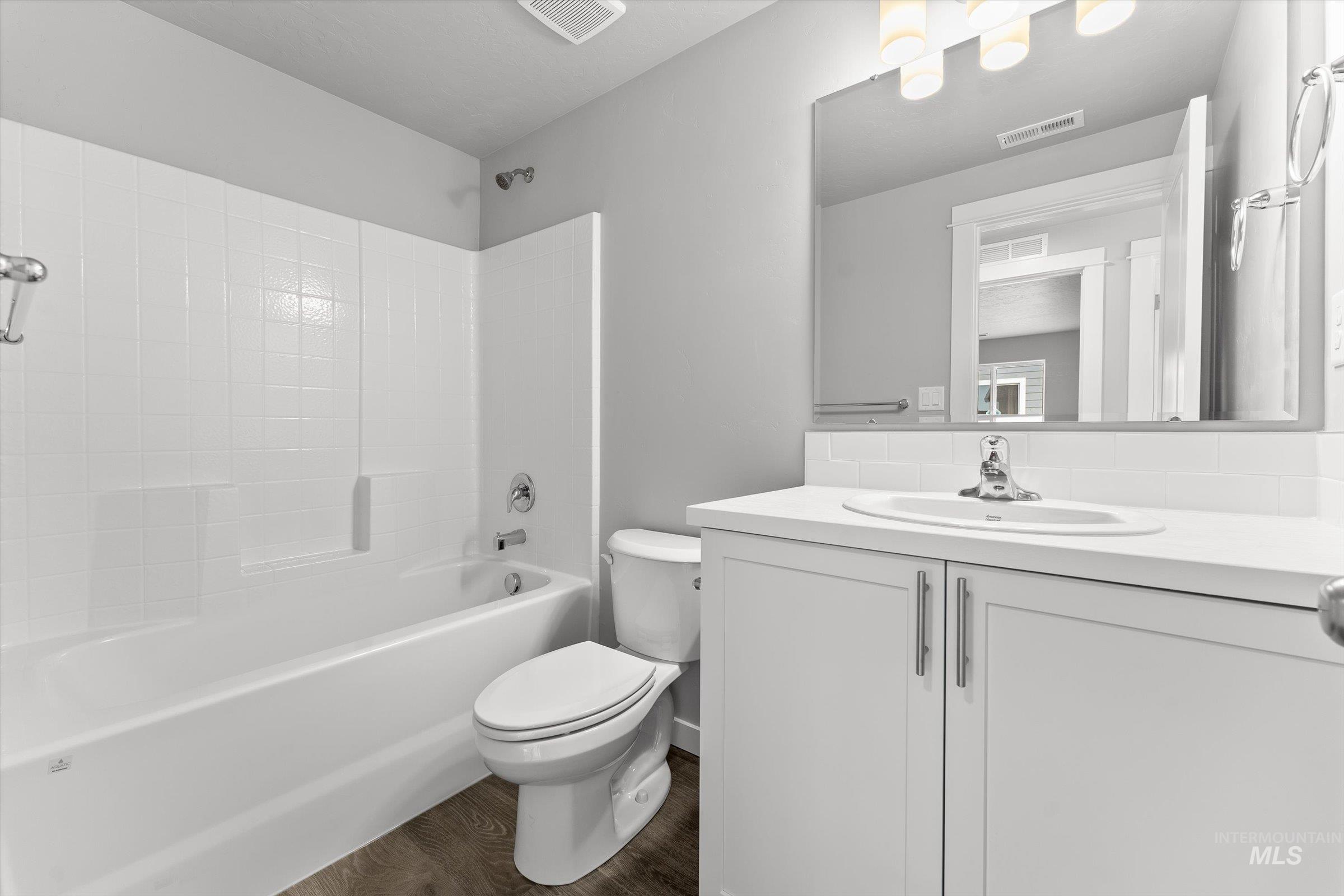 Full bathroom with vanity, dark wood-style flooring, and  shower combination