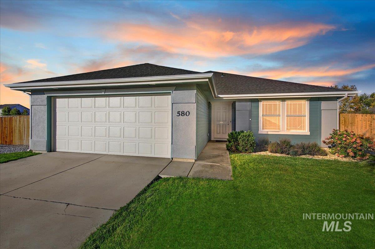 Ranch-style home featuring a garage, concrete driveway, and roof with shingles